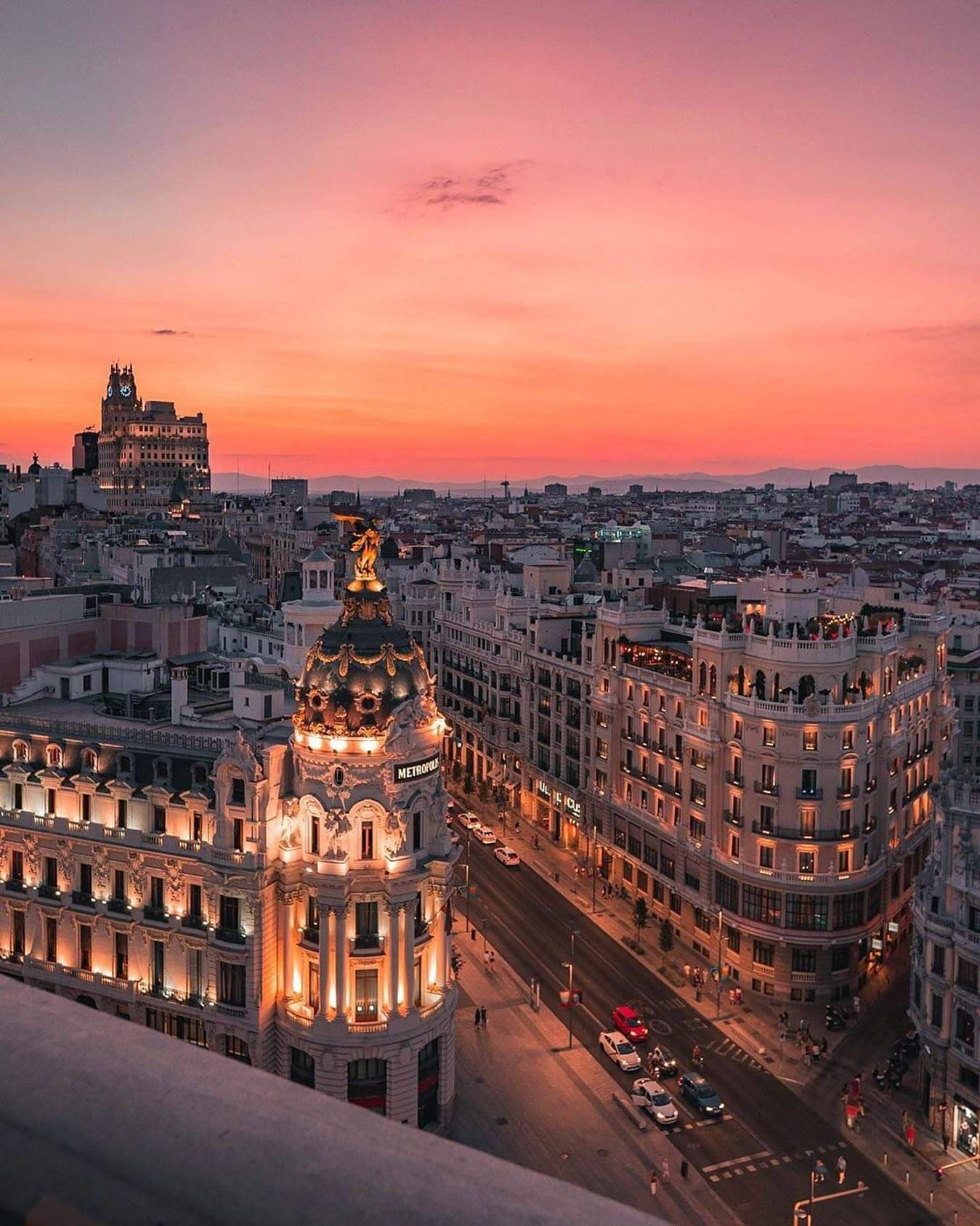 Madrid 桌布 壁紙 — 壯麗的日落將馬德里的歷史建築沐浴在溫暖的粉紅色和橙色色調中，城市的燈光開始閃耀。