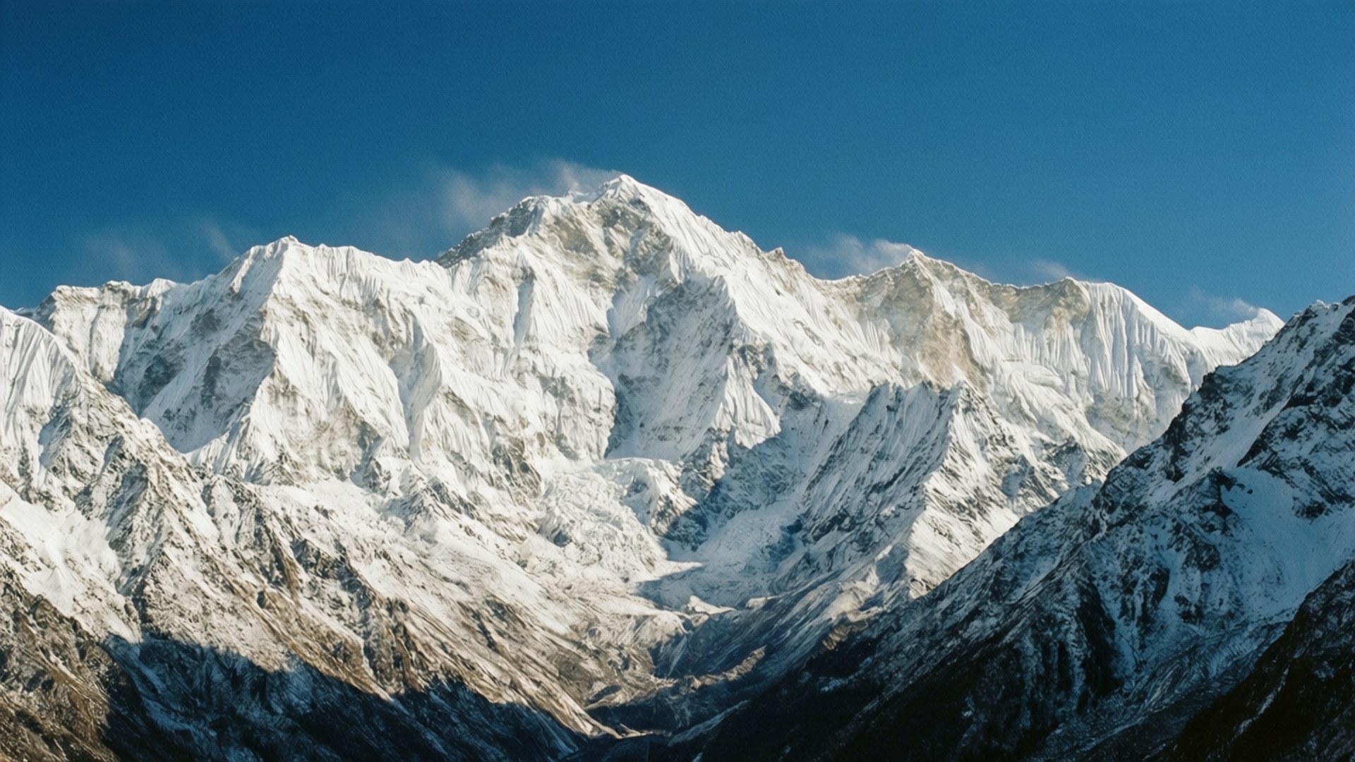 壯麗雪峰 壁紙 — 雄偉的雪山山脈以尖銳的山脊和深邃的陰影刺穿清澈的藍天。