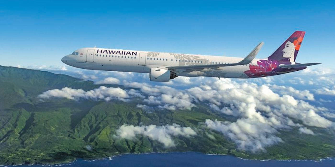 夏威夷航空飛機飛越綠色山脈和海洋雲層。