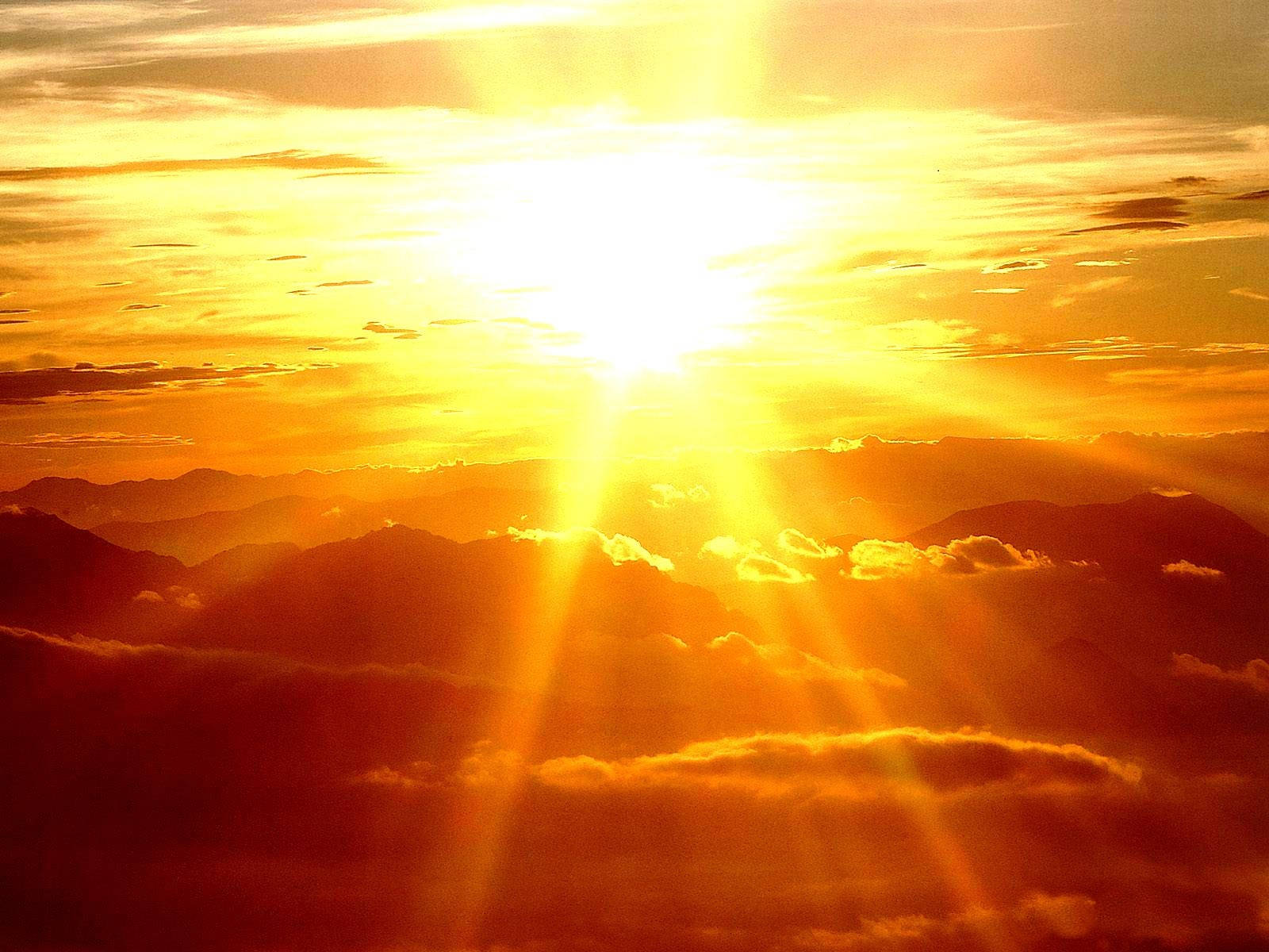 日落 桌布 壁紙 — 夕陽下，一道燦爛的陽光穿透金色雲層，照耀在層層疊疊的山脈上。