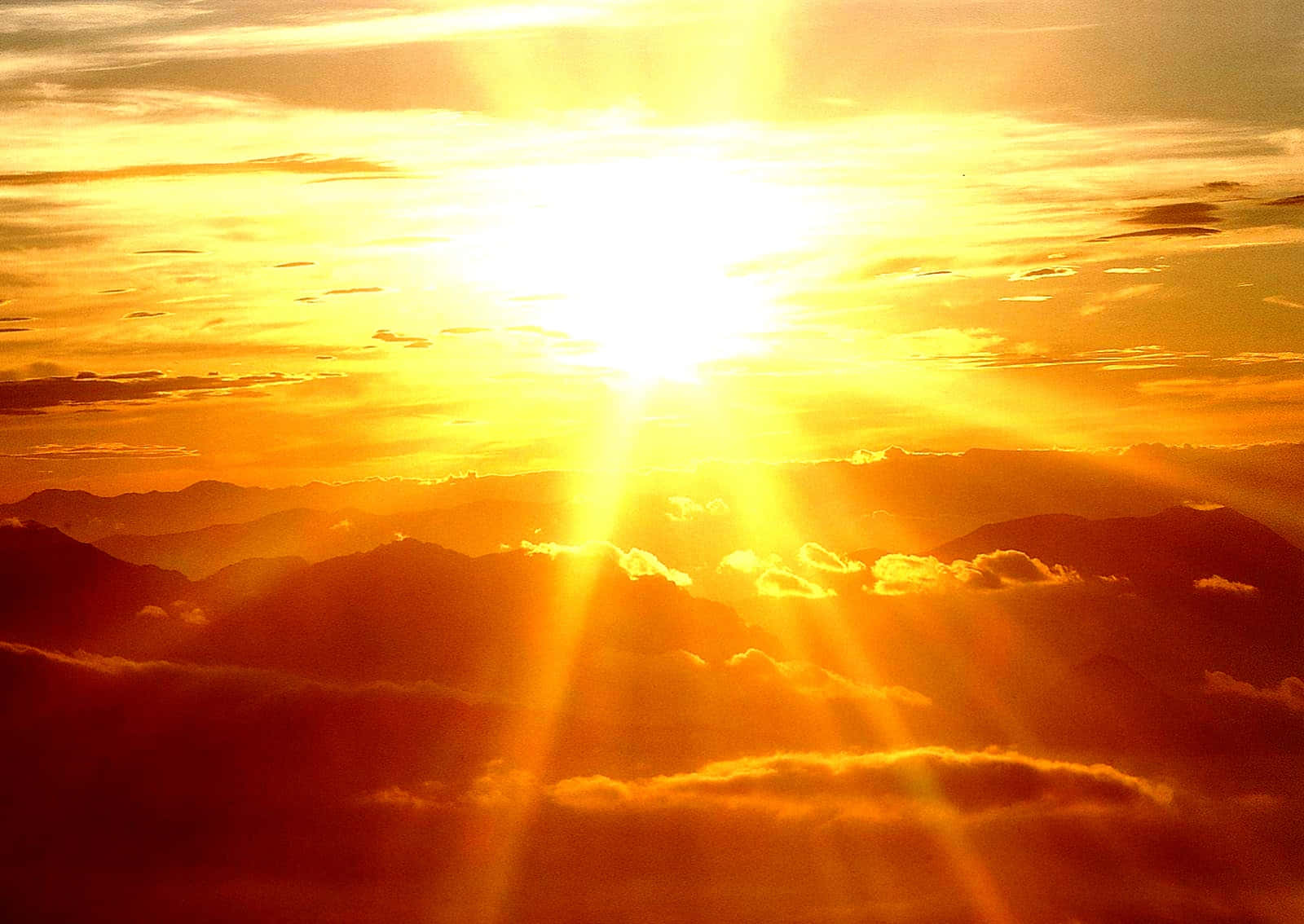 太陽 桌布 壁紙 — 夕陽下，燦爛的陽光穿透金色雲層，照耀在層層疊疊的山脈之上。