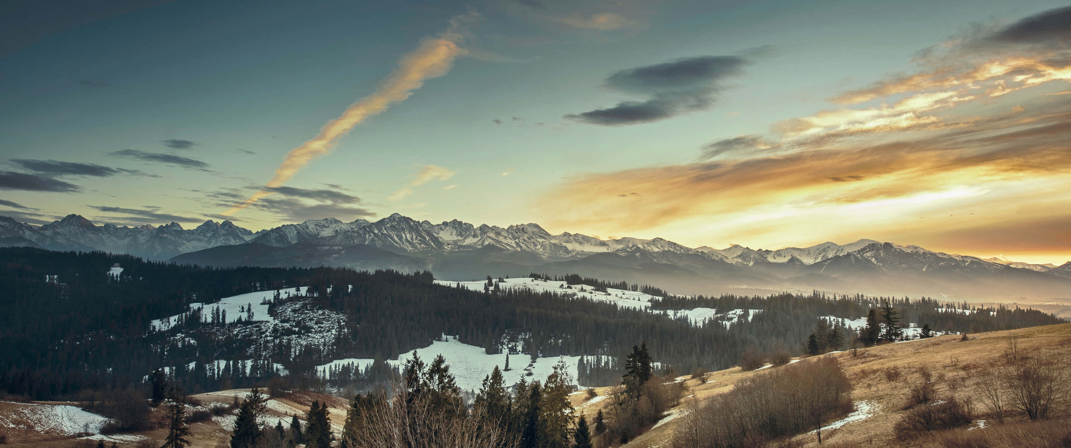3440x1440p Seattle 桌布 壁紙 — 夕陽下，白雪覆蓋的山峰聳立在常綠樹林和金色山丘的峽谷後方。