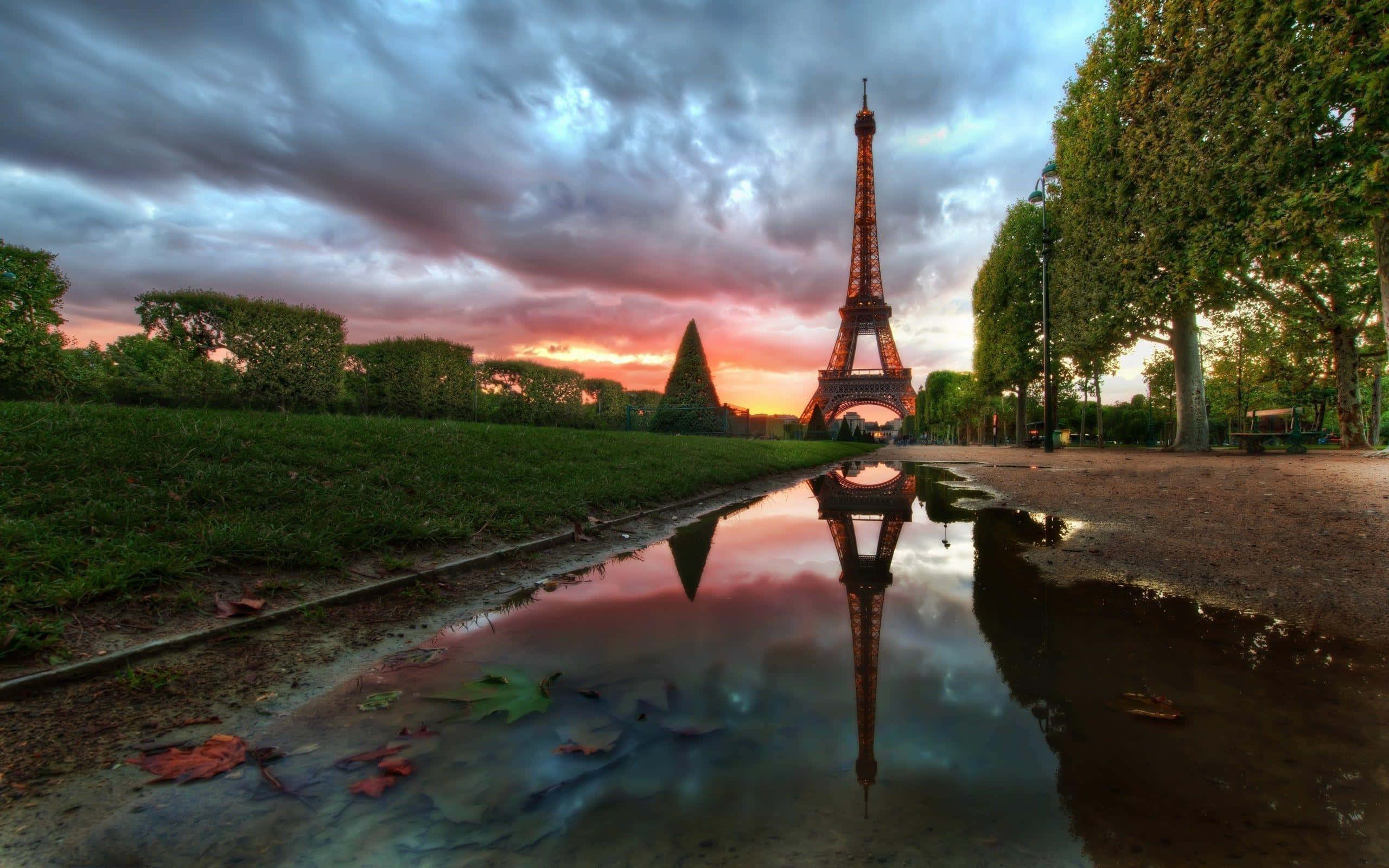 Eiffel Tower 桌布 壁紙 — 夕陽下，艾菲爾鐵塔倒映在水坑中，伴隨著戲劇性的雲彩和秋葉。
