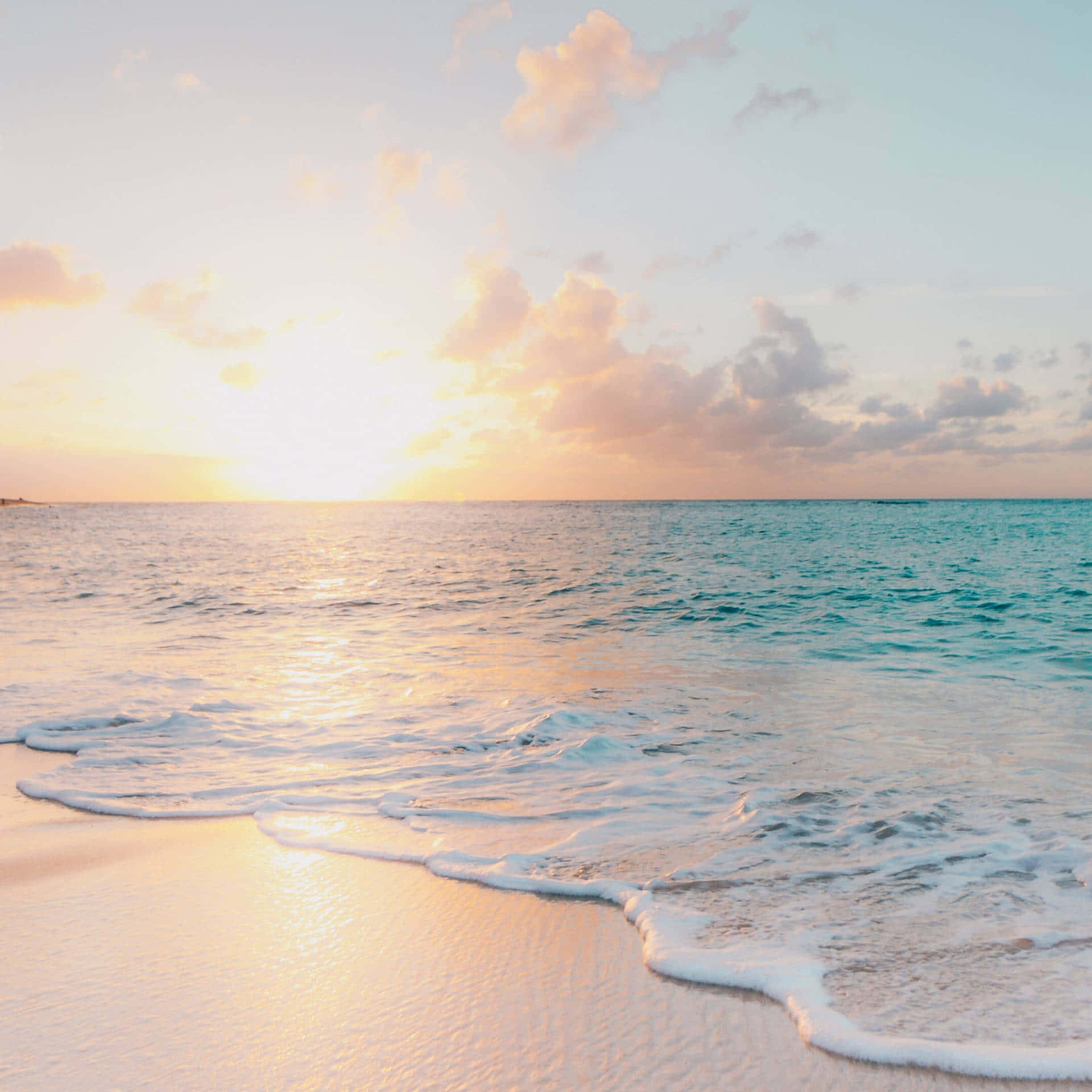 夕陽下海浪拍打沙灘的海灘 壁紙