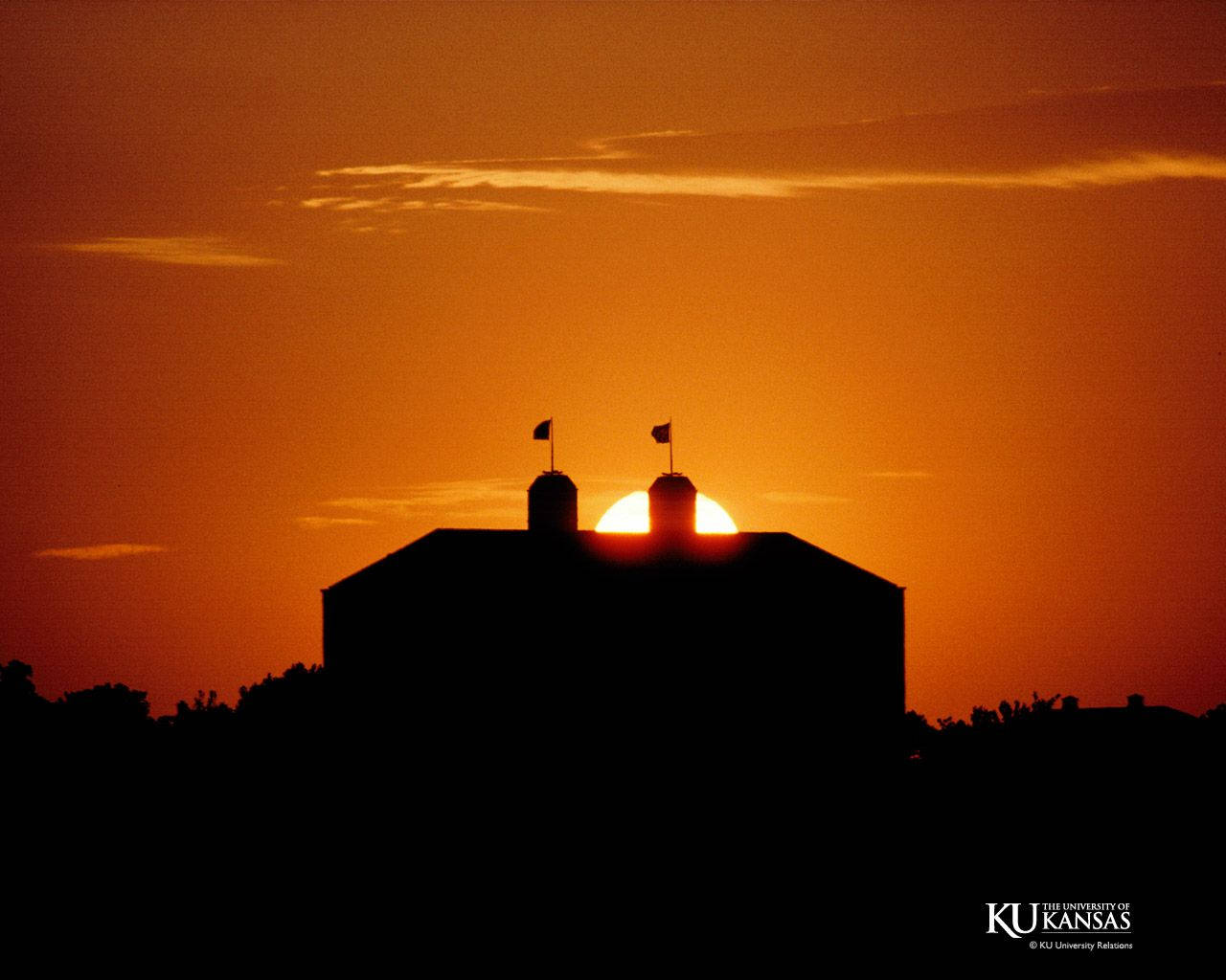 Silhouette 桌布 壁紙 — 夕陽下穀倉的剪影，太陽完美地框在兩個筒倉之間，映襯著火紅的橙色天空。