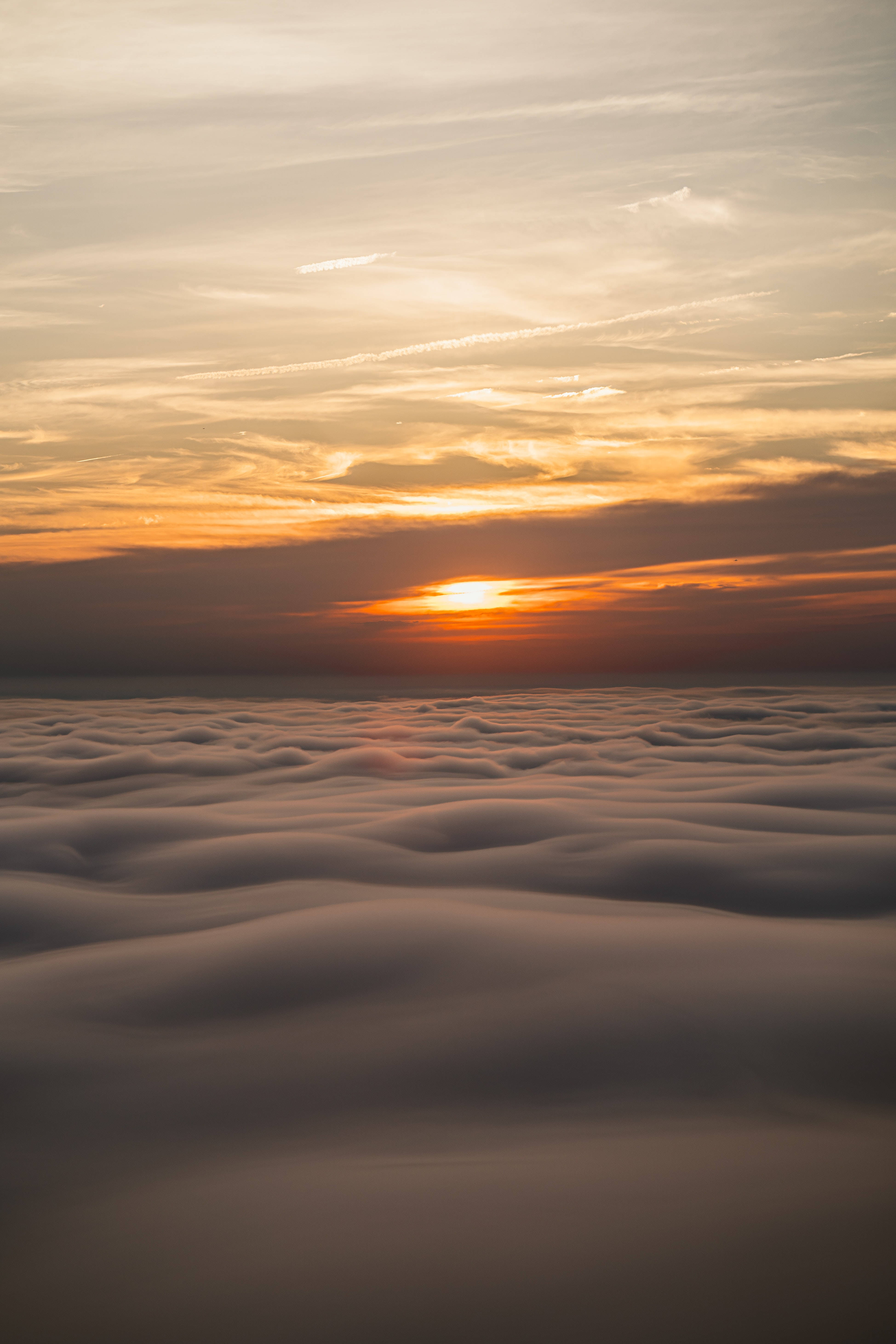雲朵 桌布 壁紙 — 夕陽以溫暖的橙色和金色塗抹天空，沉入柔軟翻滾的雲海之下。