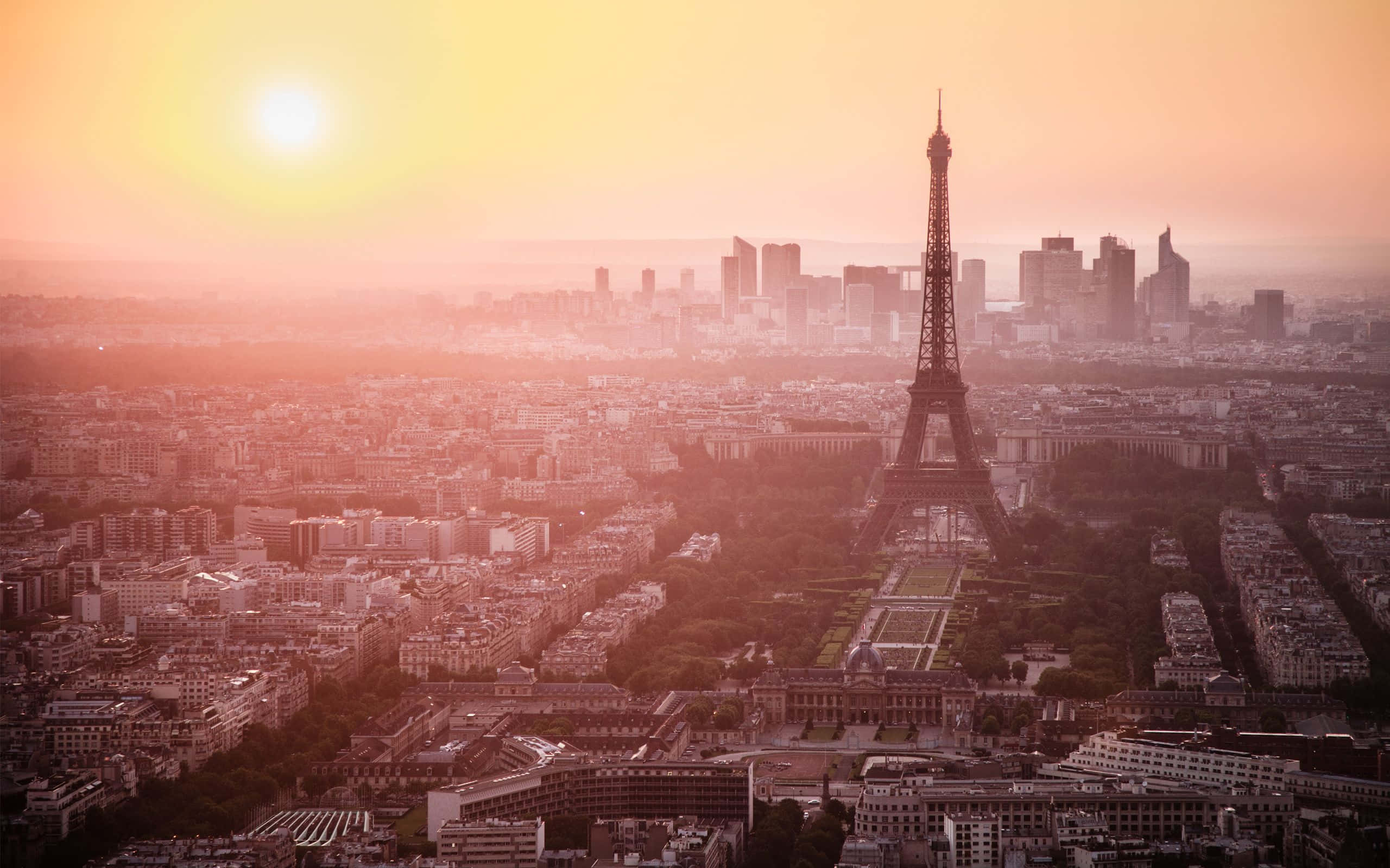 Paris Desktop 桌布 壁紙 — 夕陽以溫暖的金色光芒沐浴著艾菲爾鐵塔和巴黎天際線，帶有朦朧的大氣光暈。