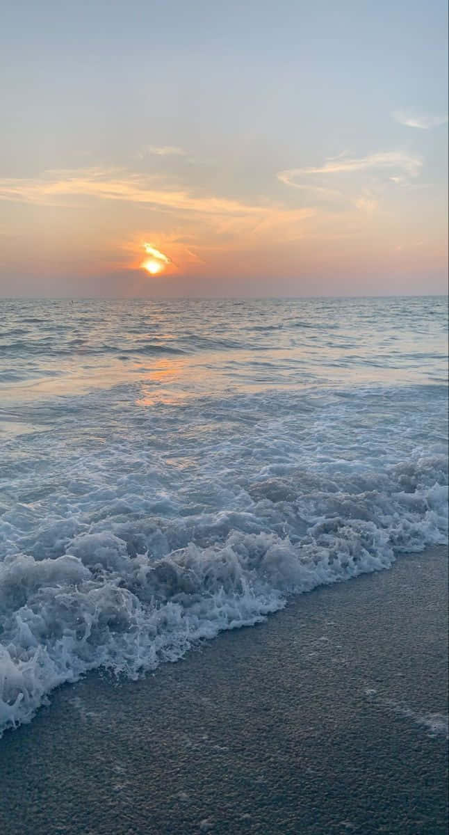自然 桌布 壁紙 — 夕陽以溫暖色調塗抹天空，溫柔的海浪拍打著沙灘。