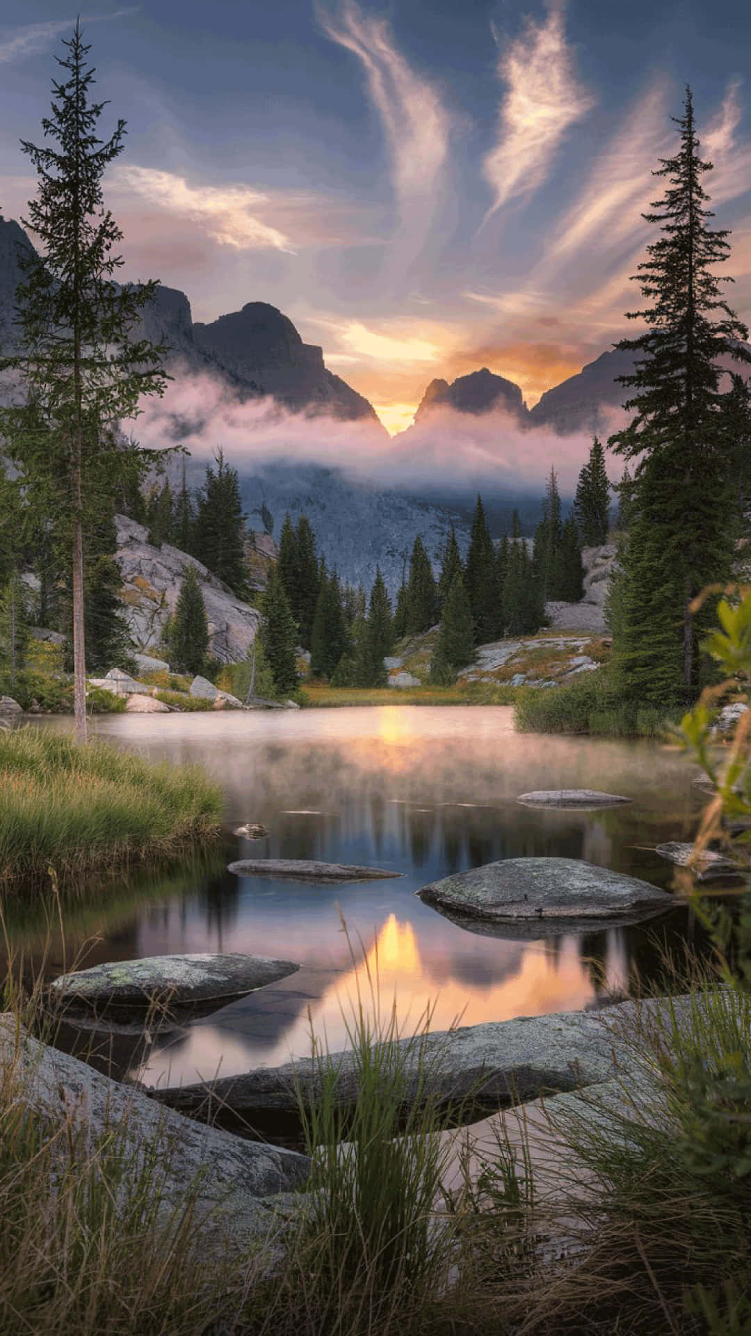 Serene mountain lake at sunrise  nature wallpaper 壁紙 — 夕陽以溫暖色調描繪山峰和雲彩，倒映在被常綠樹環繞的霧氣湖中。