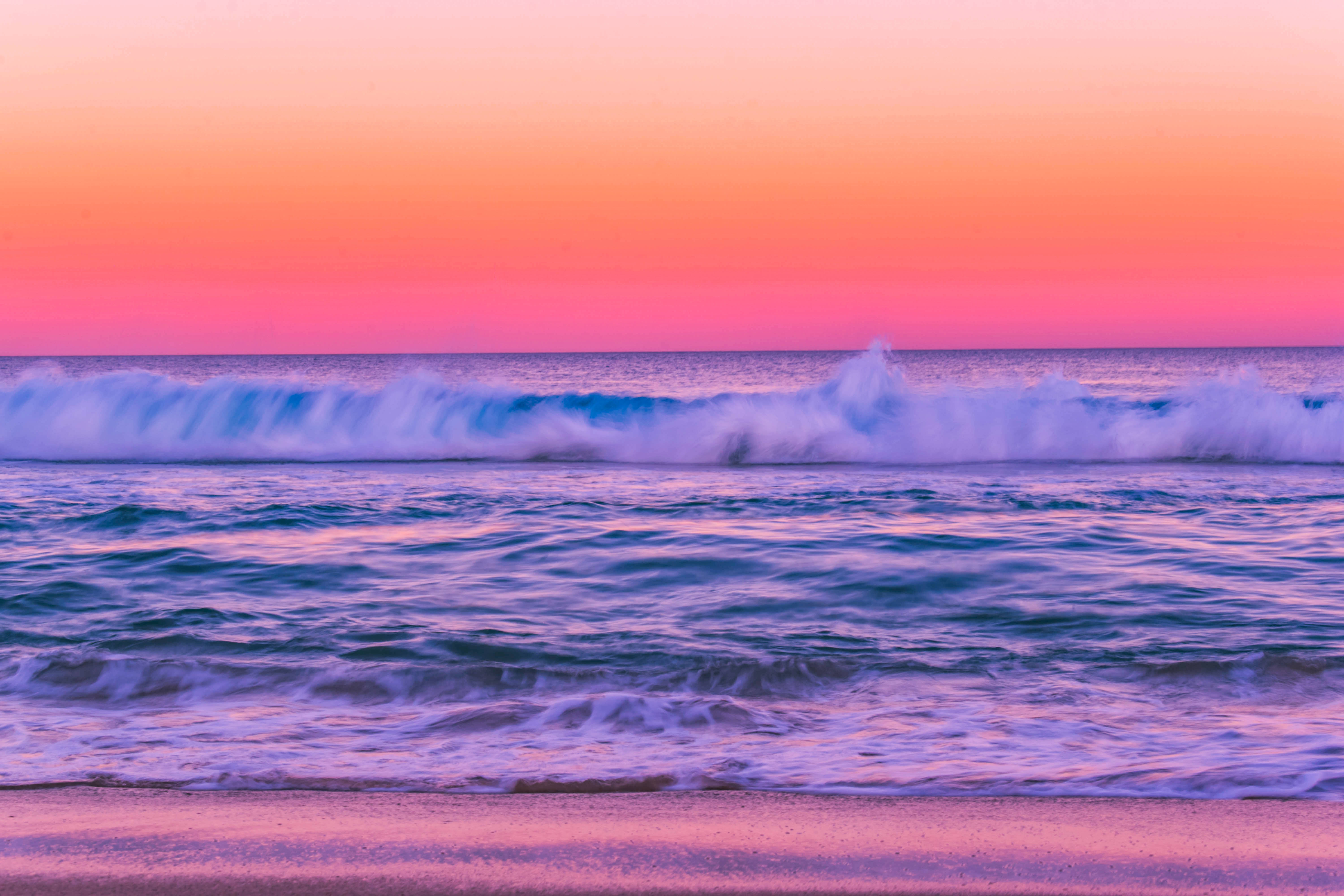 水 桌布 壁紙 — 夕陽以粉紅和紫色調描繪海洋，海浪拍打沙灘。