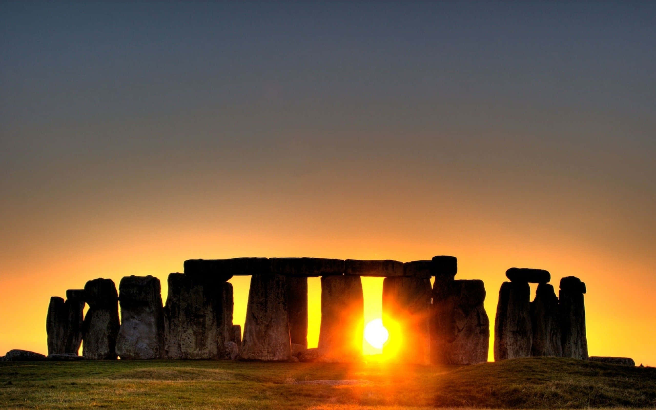 England 桌布 壁紙 — 夕陽在古老的立石背後發光，在草地上投下長長的影子。