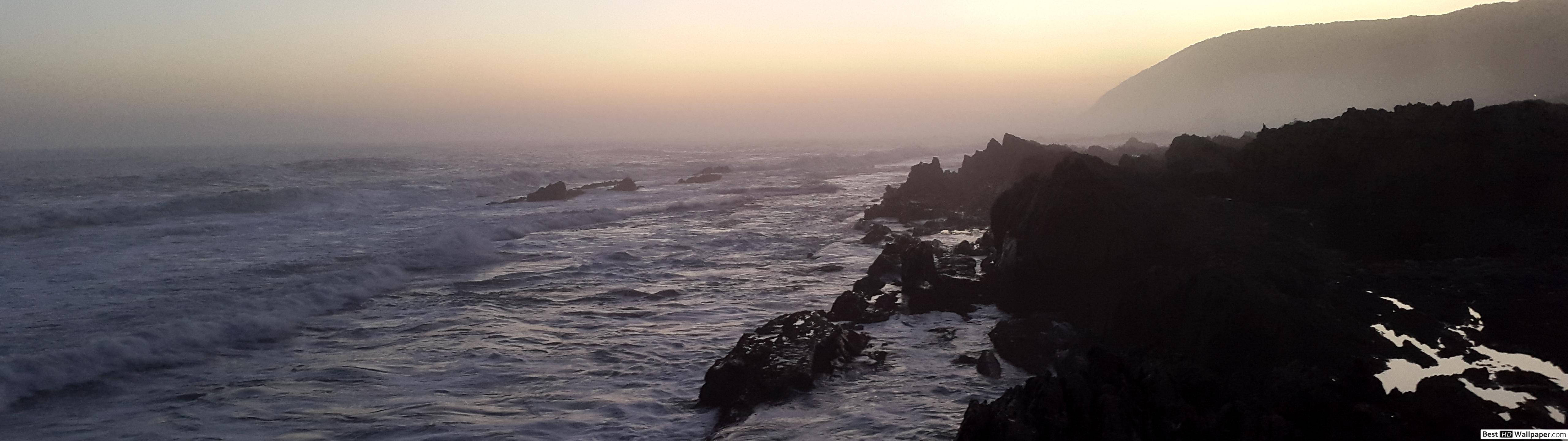 自然 桌布 壁紙 — 夕陽在洶湧的海浪上投下溫暖的光芒，拍打著黑暗的火山懸崖。
