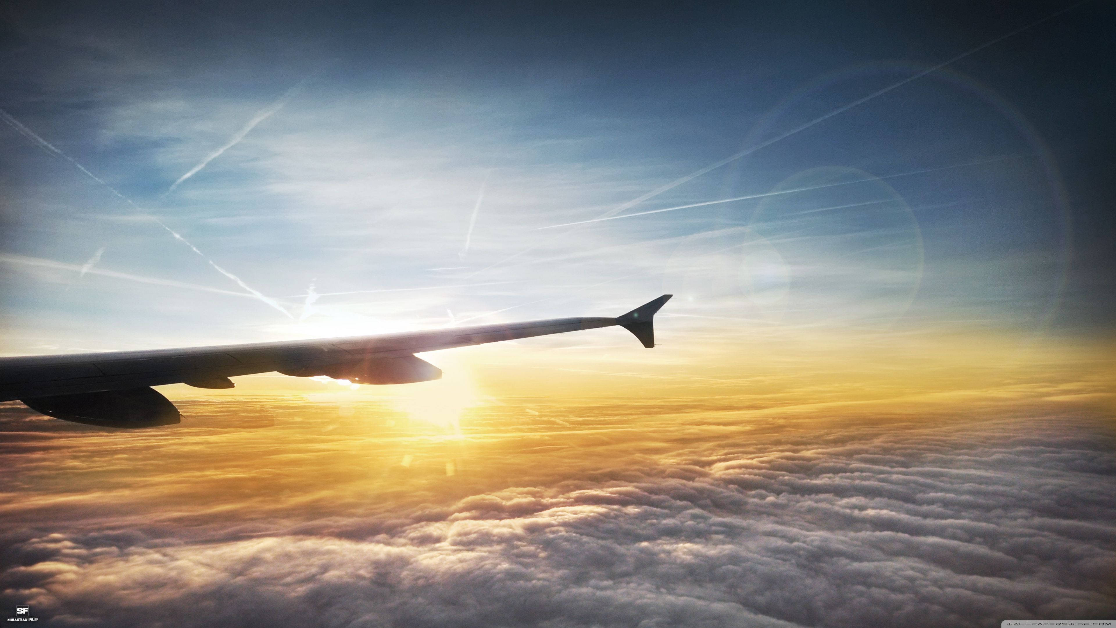 4K 飛機壁紙 桌布 壁紙 — 夕陽在飛機機翼後方發光，翱翔於無盡的金色雲層之上。