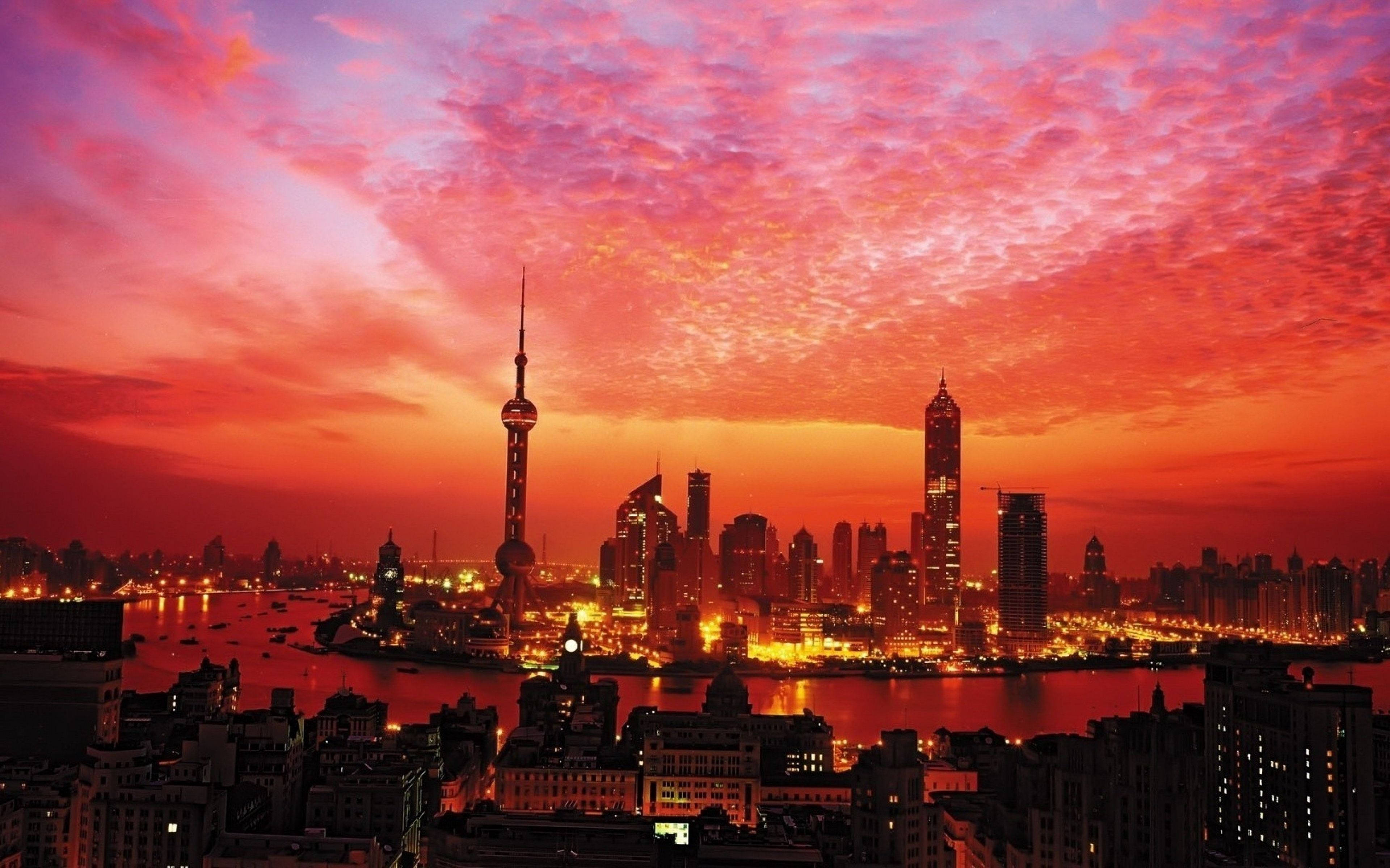 Shanghai 桌布 壁紙 — 夕陽將上海天際線染成火紅和橙色，城市燈光倒映在黃浦江上。