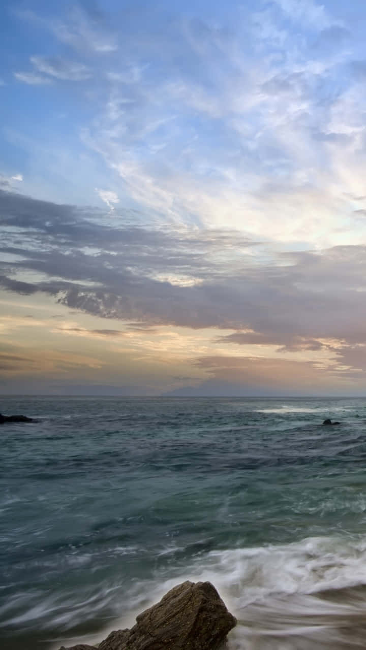 加州 桌布 壁紙 — 夕陽將天空染成柔和的金色和藍色，海浪拍打著岸邊的岩石。