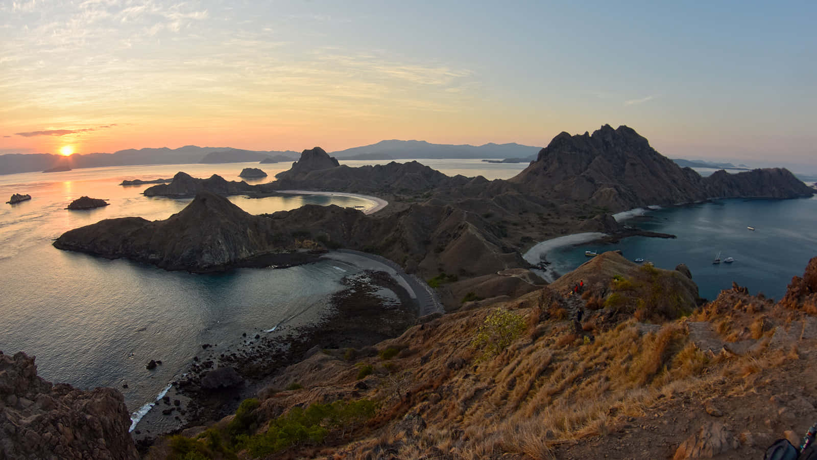 島嶼 桌布 壁紙 — 夕陽將天空染成橙色，崎嶇的火山島和碧綠的海水蜿蜒曲折，形成隱蔽的海灣。