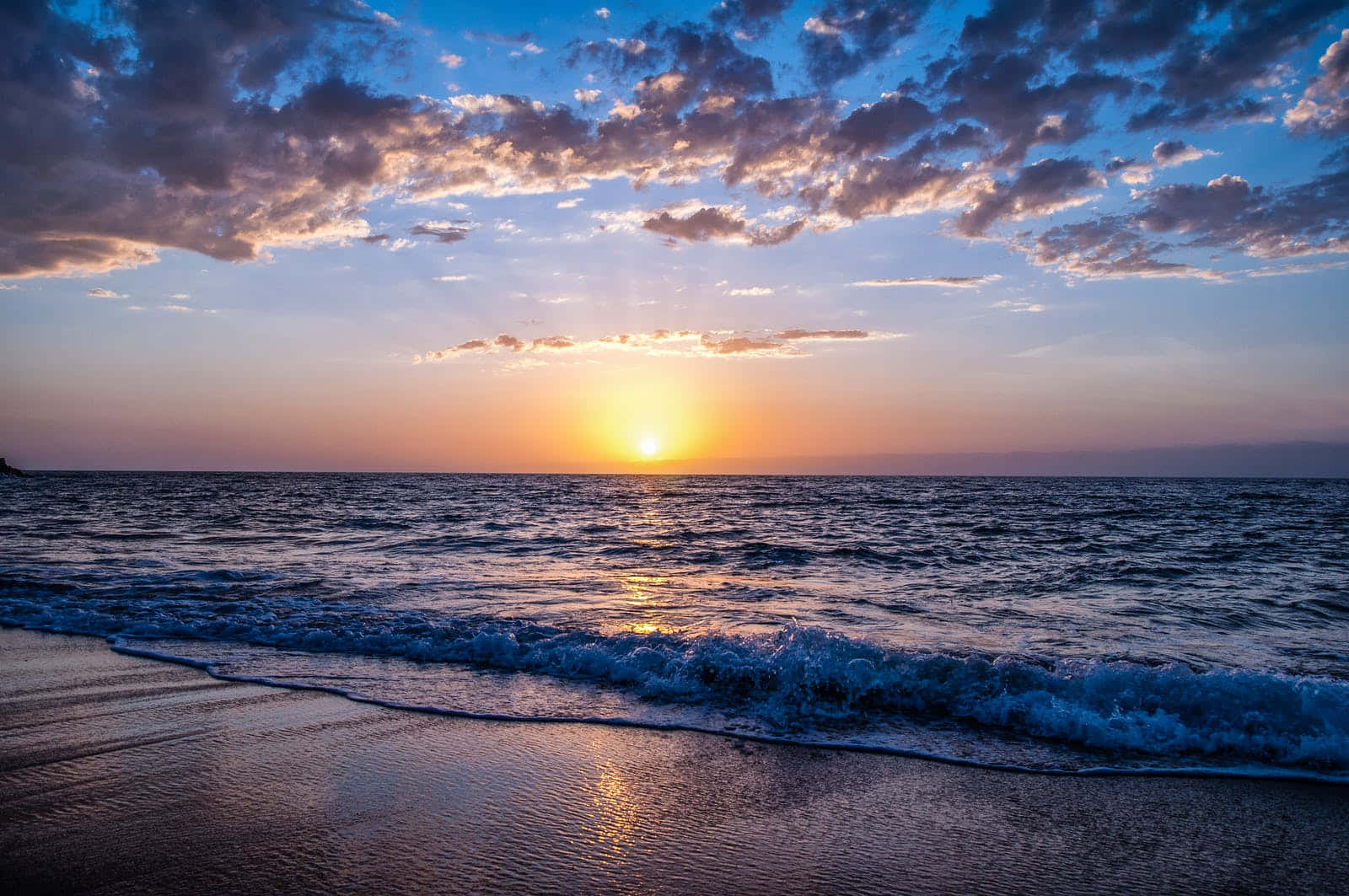 Cute Sunset 桌布 壁紙 — 夕陽將天空染成橙色和紫色，海浪拍打濕漉漉的沙灘。