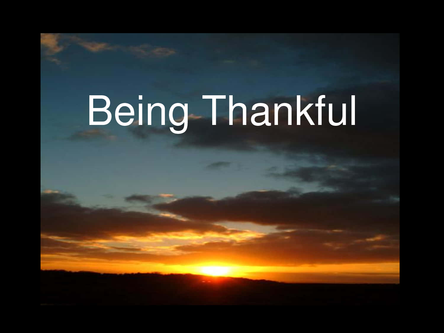 Thankful 桌布 壁紙 — 夕陽將天空染成火熱的橙色和深藍色，雲朵在剪影地平線上方發光，並帶有文字疊加。