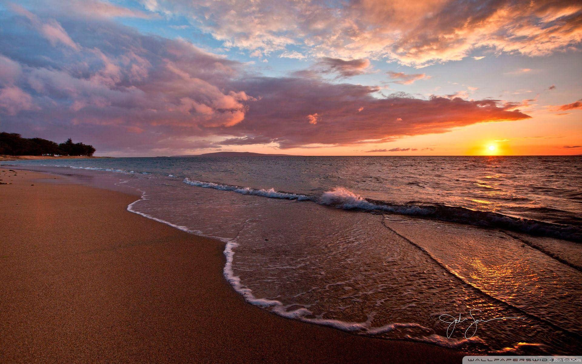 海灘日落 桌布 壁紙 — 夕陽將天空染成火熱的橙色和粉紅色，海浪輕輕拍打著沙灘。