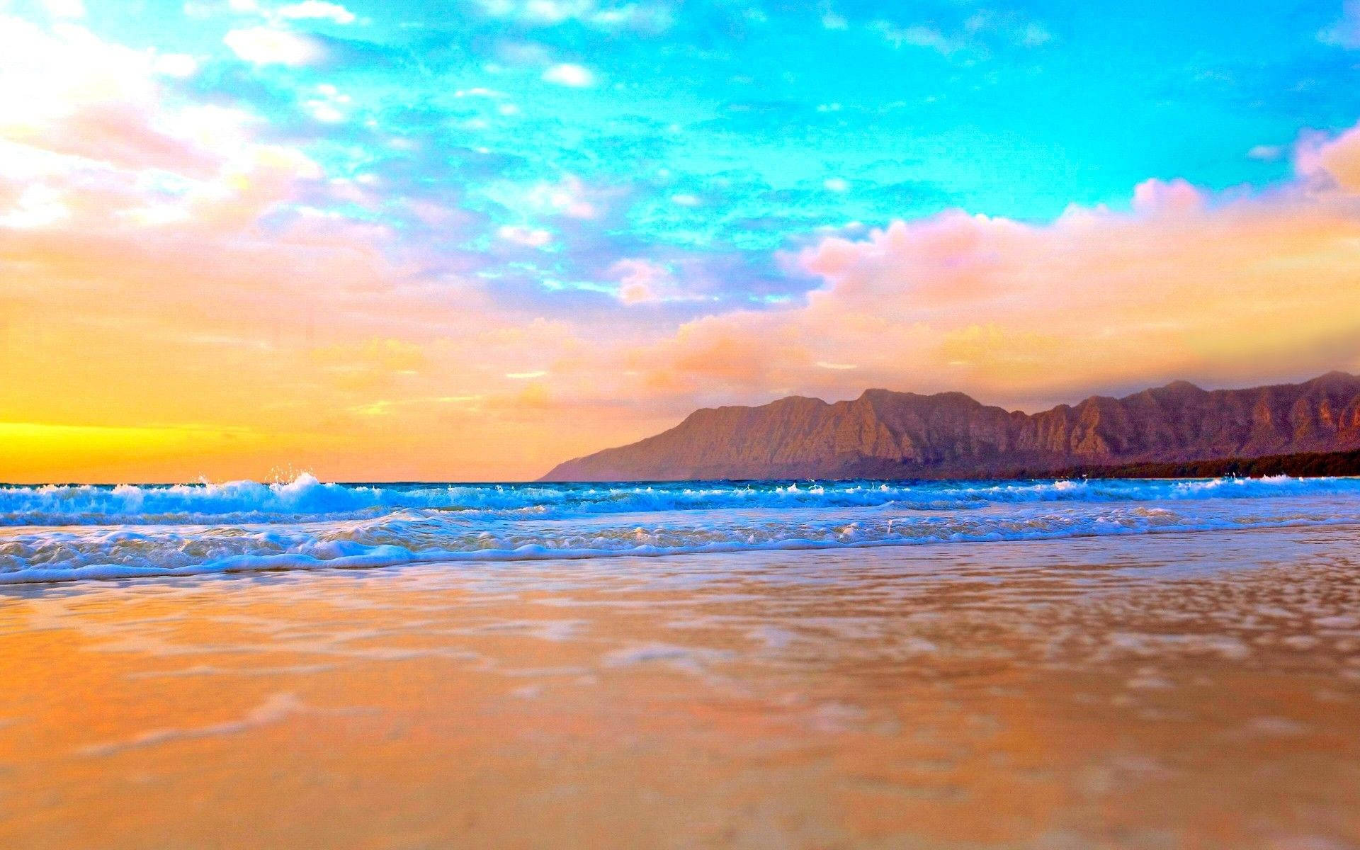 Relaxing Desktop 桌布 壁紙 — 夕陽將天空染成火熱的橙色和藍綠色，海浪拍打著金色的沙灘，遠山形成剪影。