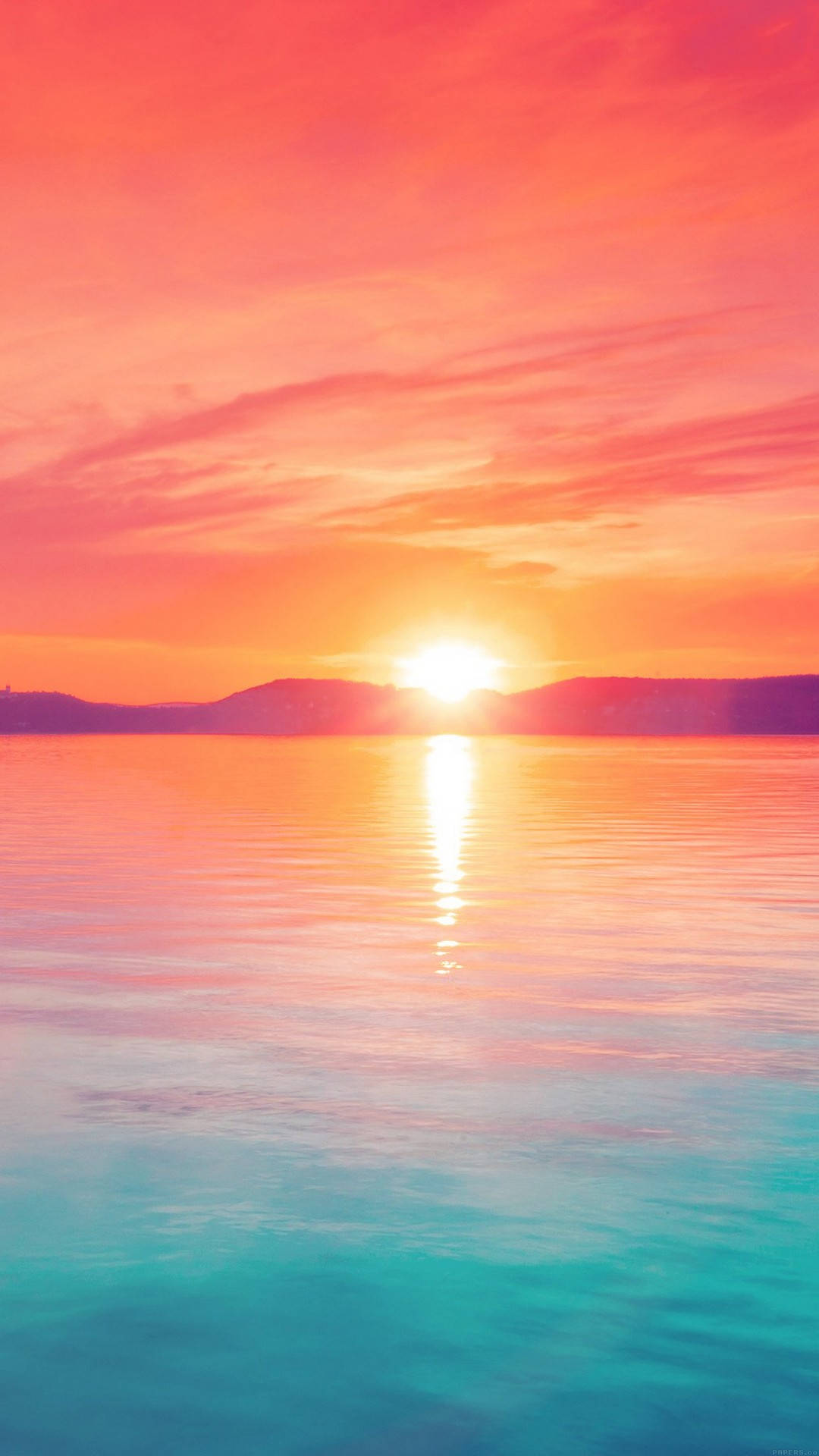 夕陽天空 桌布 壁紙 — 夕陽將天空染成火熱的粉紅色和橙色，太陽落到遠山之後，在平靜的碧綠水面上投下一條閃爍的金色路徑。