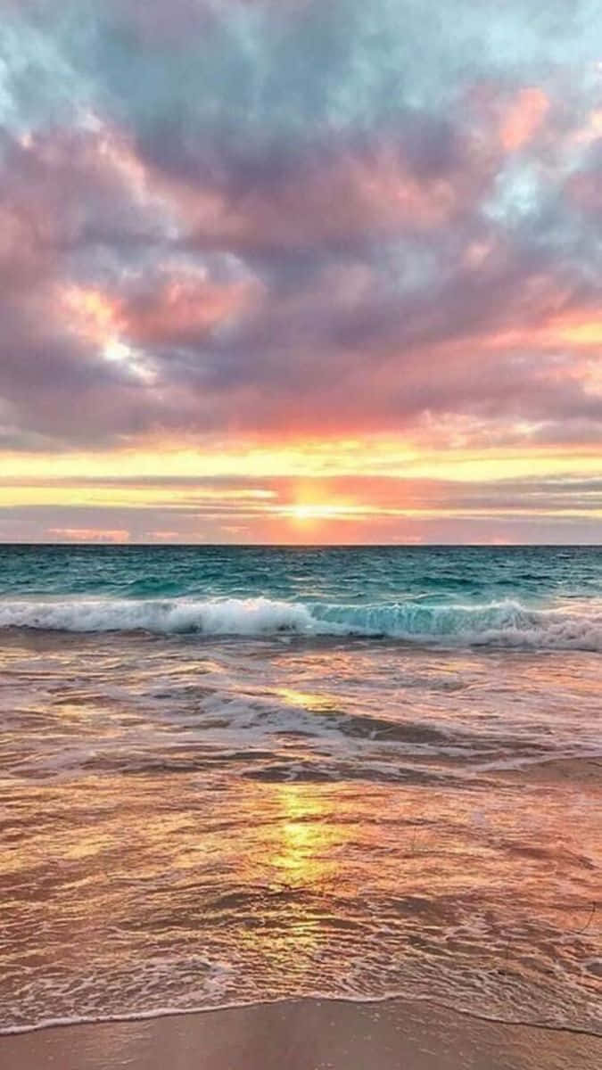 海灘 桌布 壁紙 — 夕陽將天空染成粉紅、橙色和紫色，海浪拍打沙灘，反射出金色的光芒。