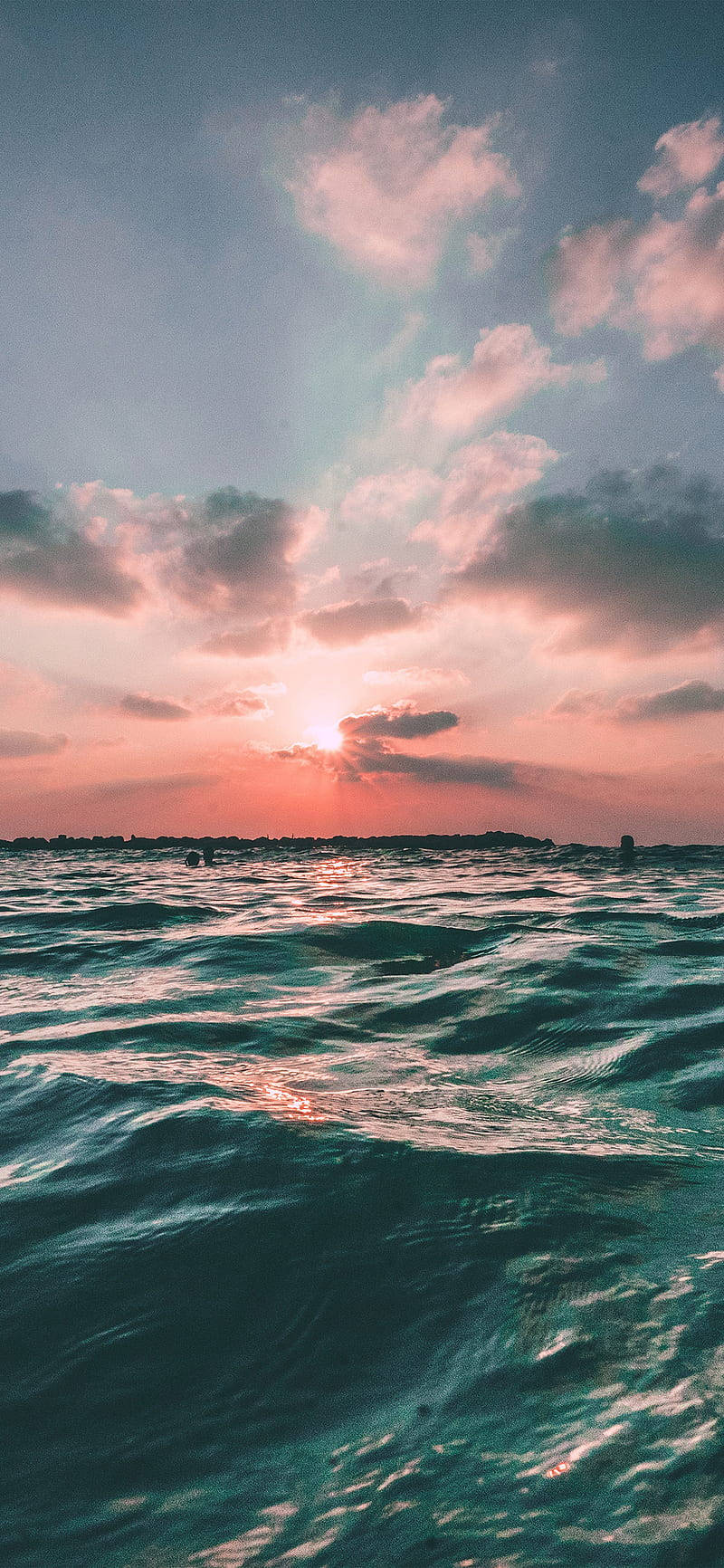 Nature iPhone 桌布 壁紙 — 夕陽將天空染成粉紅色和橙色，並反射在漣漪的藍綠色海浪上。