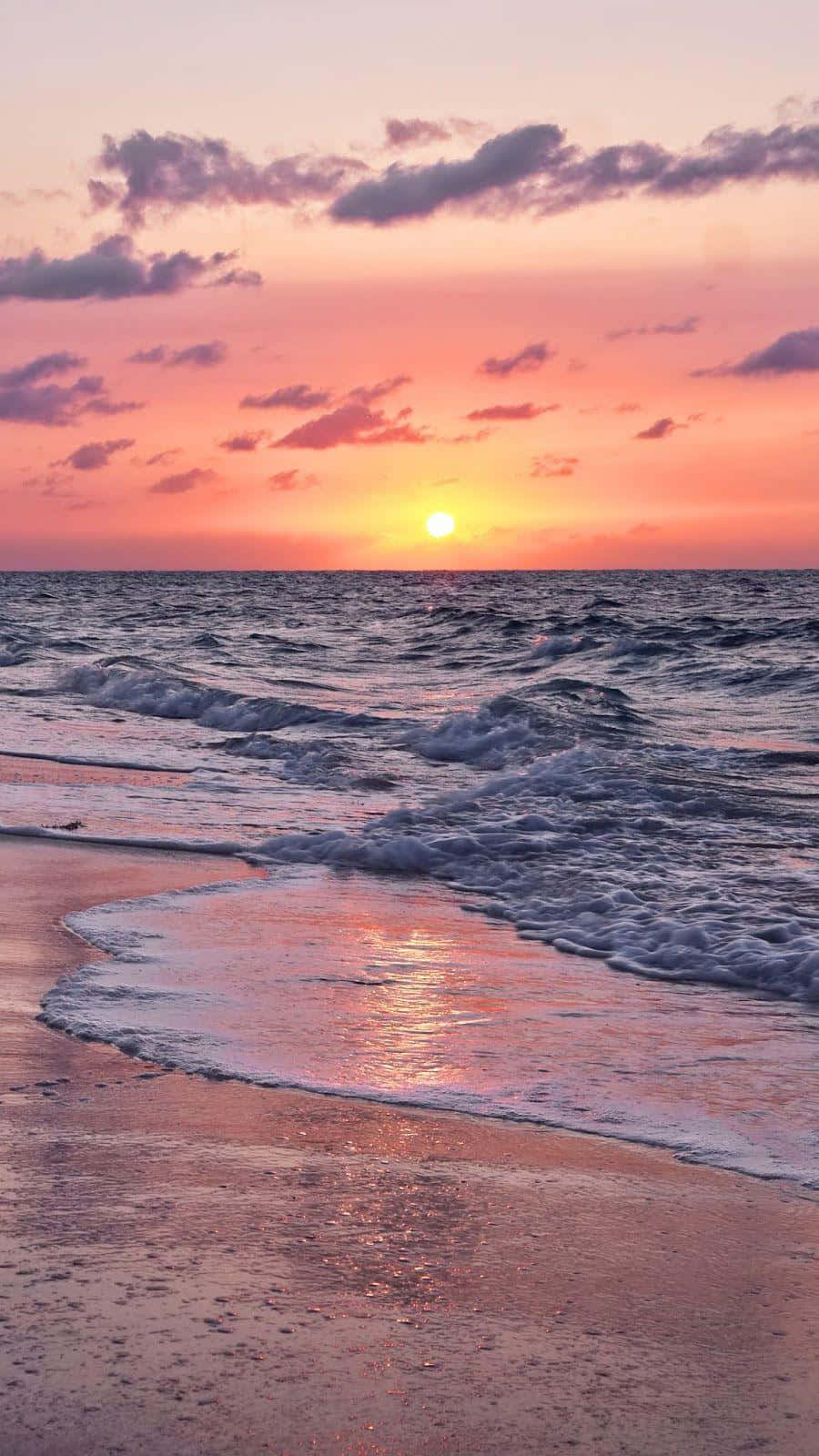 Beach Aesthetic 桌布 壁紙 — 夕陽將天空染成粉紅色和橙色，海浪拍打著濕漉漉的沙灘。