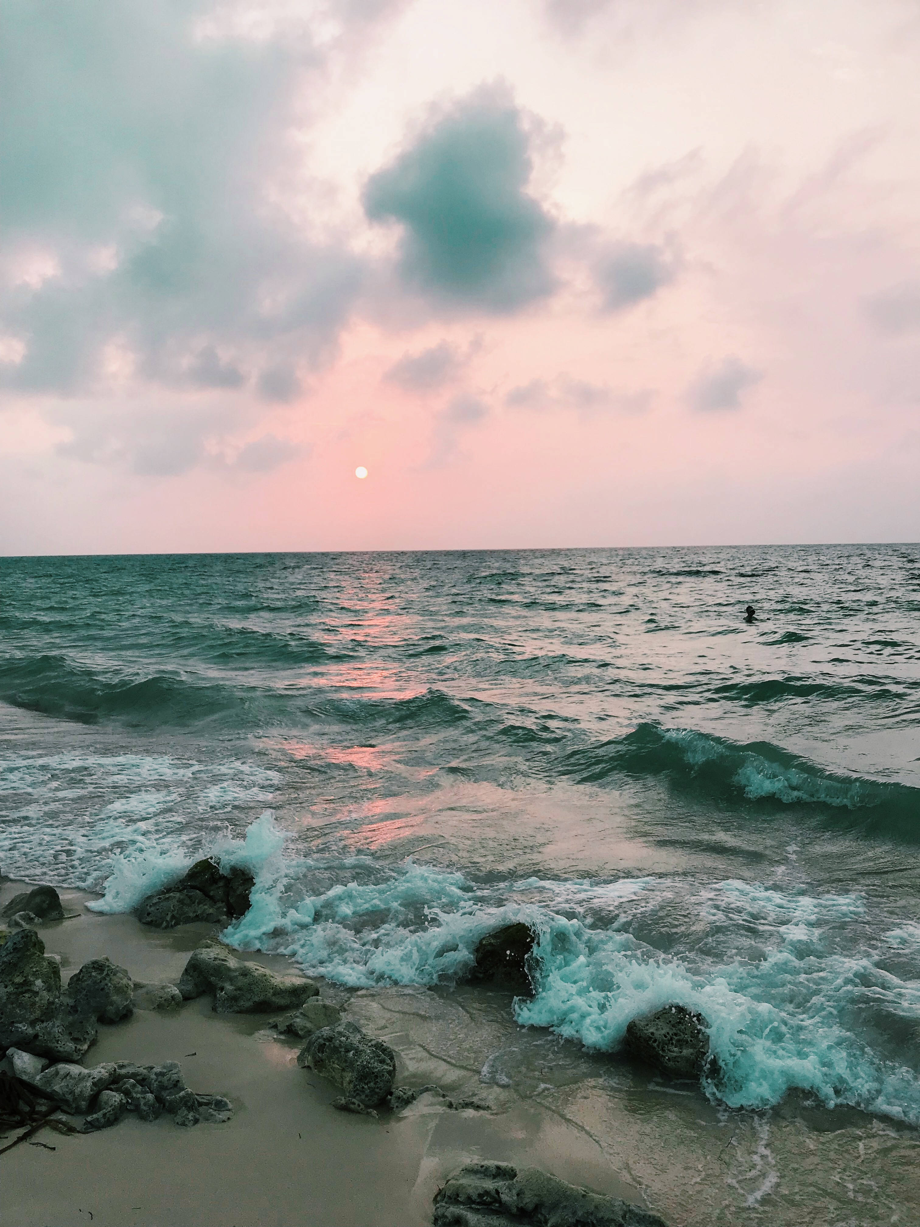 Amazing 桌布 壁紙 — 夕陽將天空染成粉紅色和藍綠色，海浪在黃昏時拍打岩石海岸。