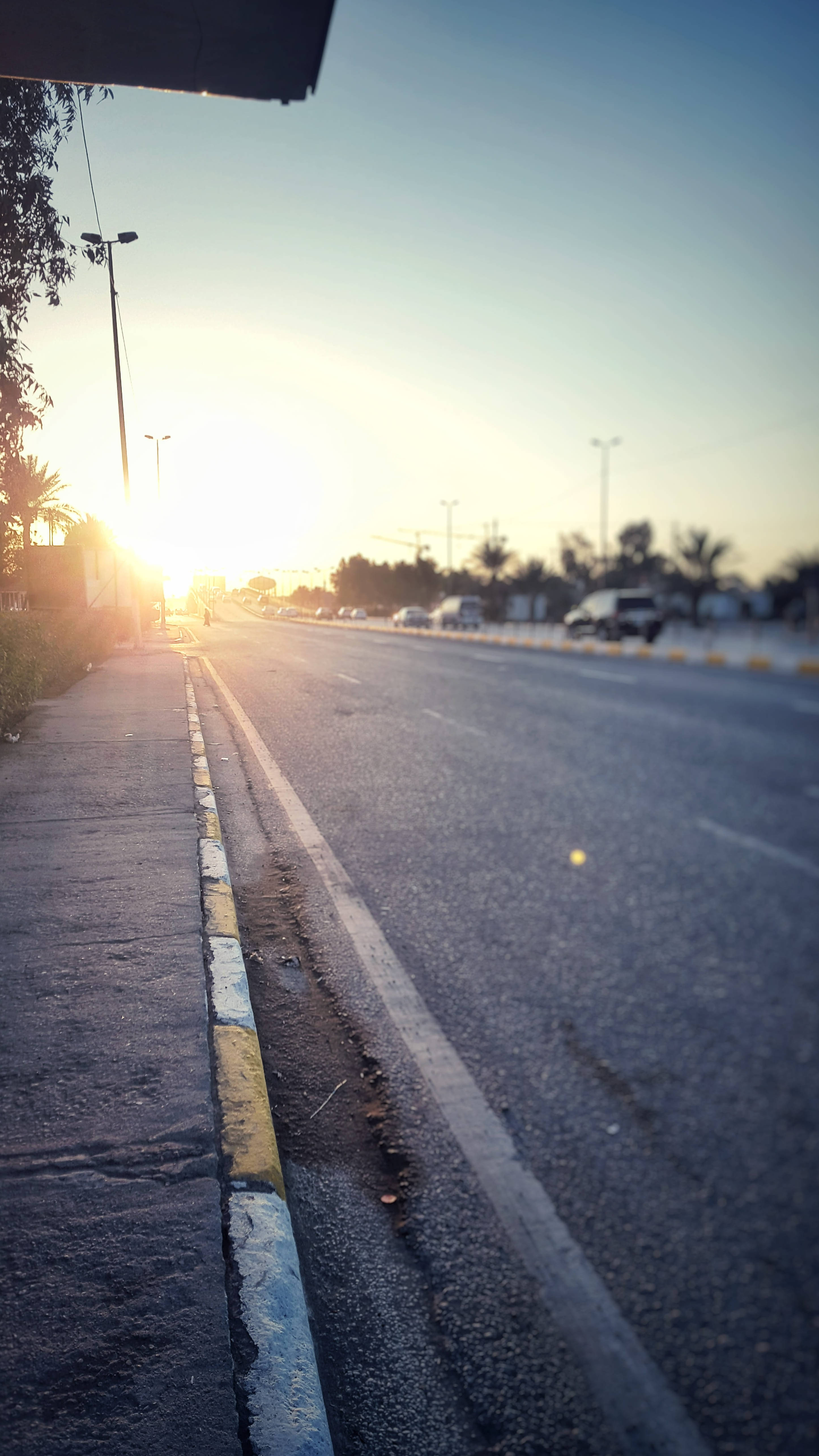Iraq 桌布 壁紙 — 夕陽將寧靜的城市道路沐浴在溫暖的金色光芒中，汽車駛向遠方。