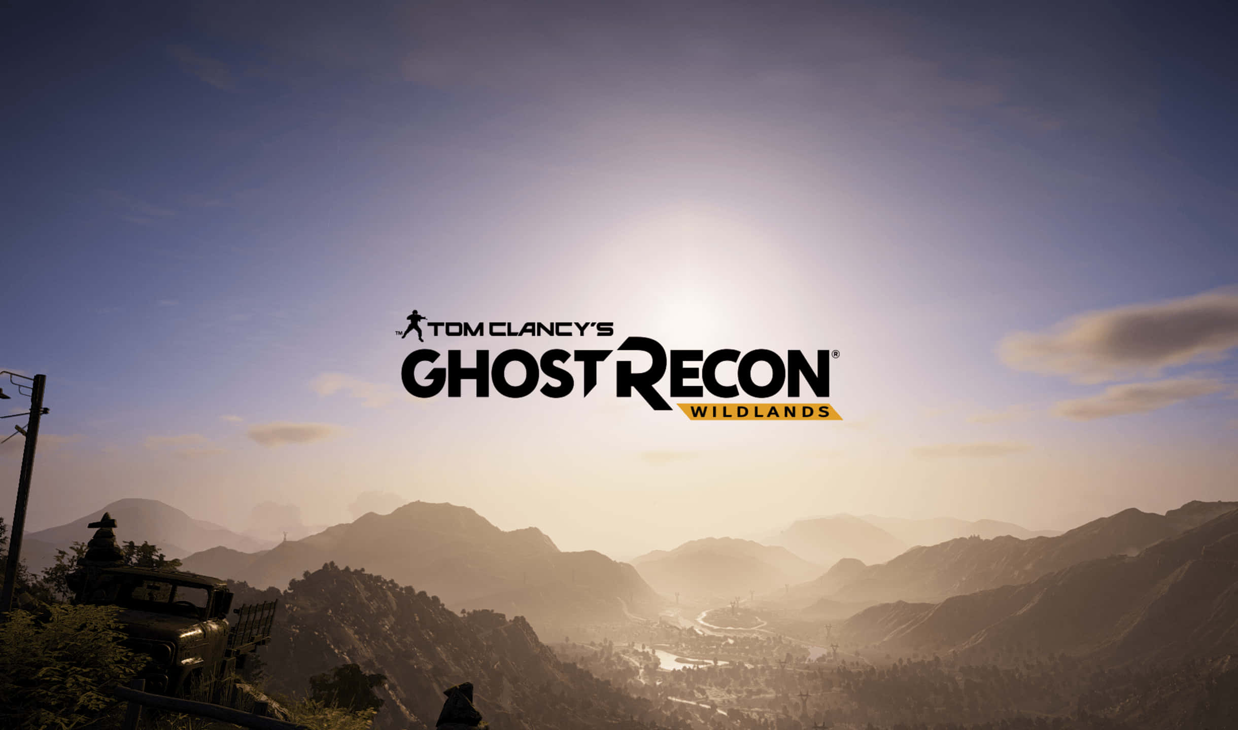 電玩遊戲 桌布 壁紙 — 夕陽將山區地形沐浴在金色光芒中，Tom Clancy's Ghost Recon Wildlands 標誌主宰天空。