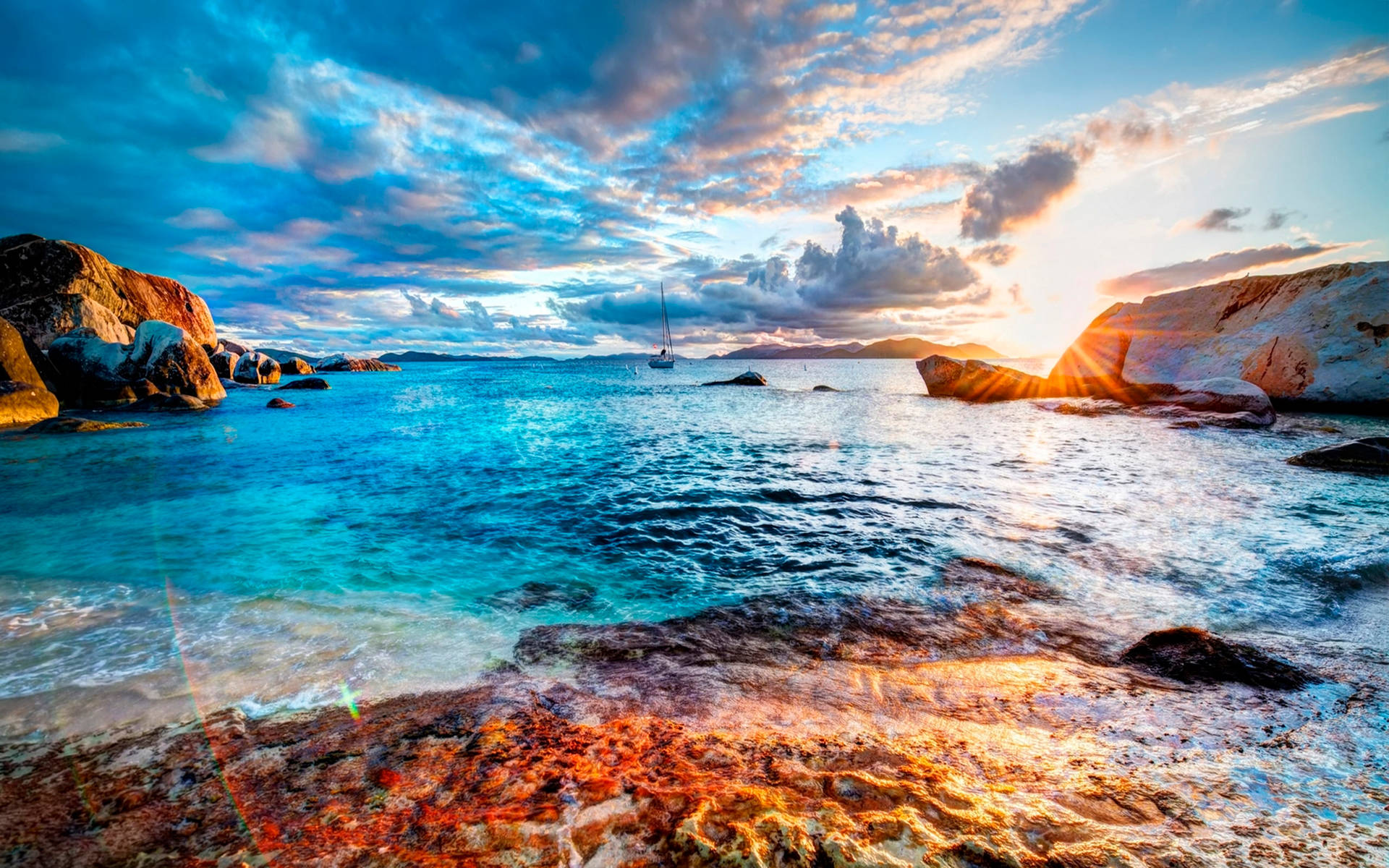 夕陽下的岩石海灣，有帆船和藍綠色海水