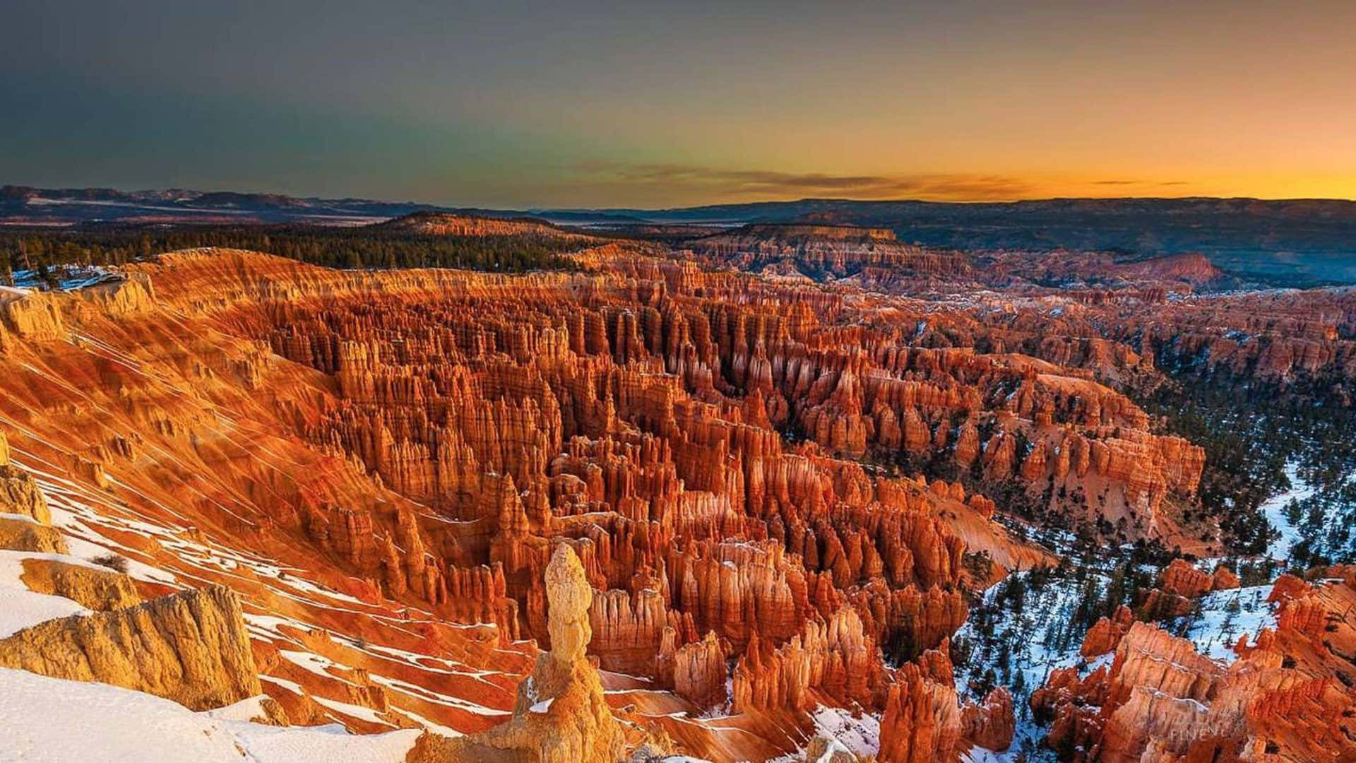 National Parks 桌布 壁紙 — 夕陽將布萊斯峽谷的橙色岩柱沐浴在溫暖的光芒中，而雪點綴著下方崎嶇的景觀。