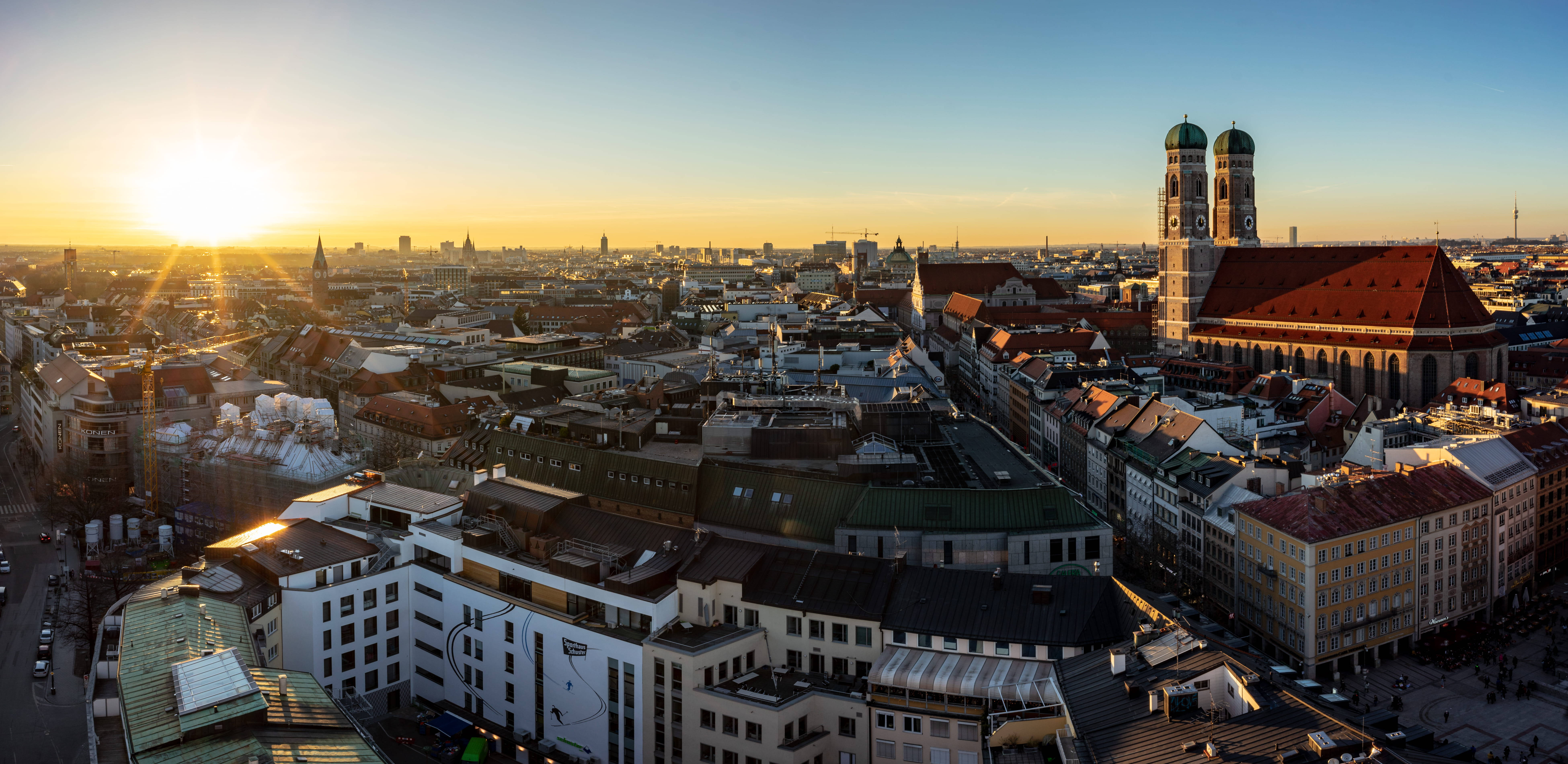 Munich 桌布 壁紙 — 夕陽將慕尼黑的屋頂沐浴在金色光芒中，聖母教堂的塔樓在晴朗的天空下巍然聳立。