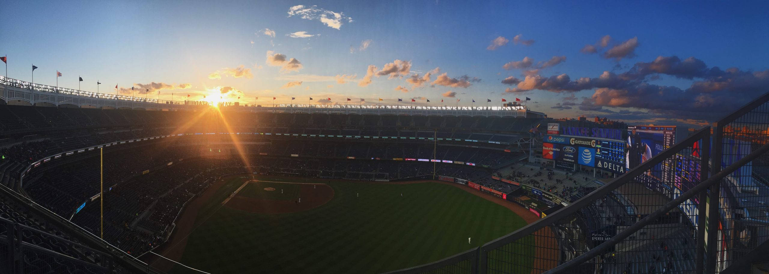 Stadium 桌布 壁紙 — 夕陽將棒球場沐浴在金色光芒中，空座位俯瞰著綠色球場和發光的記分板。