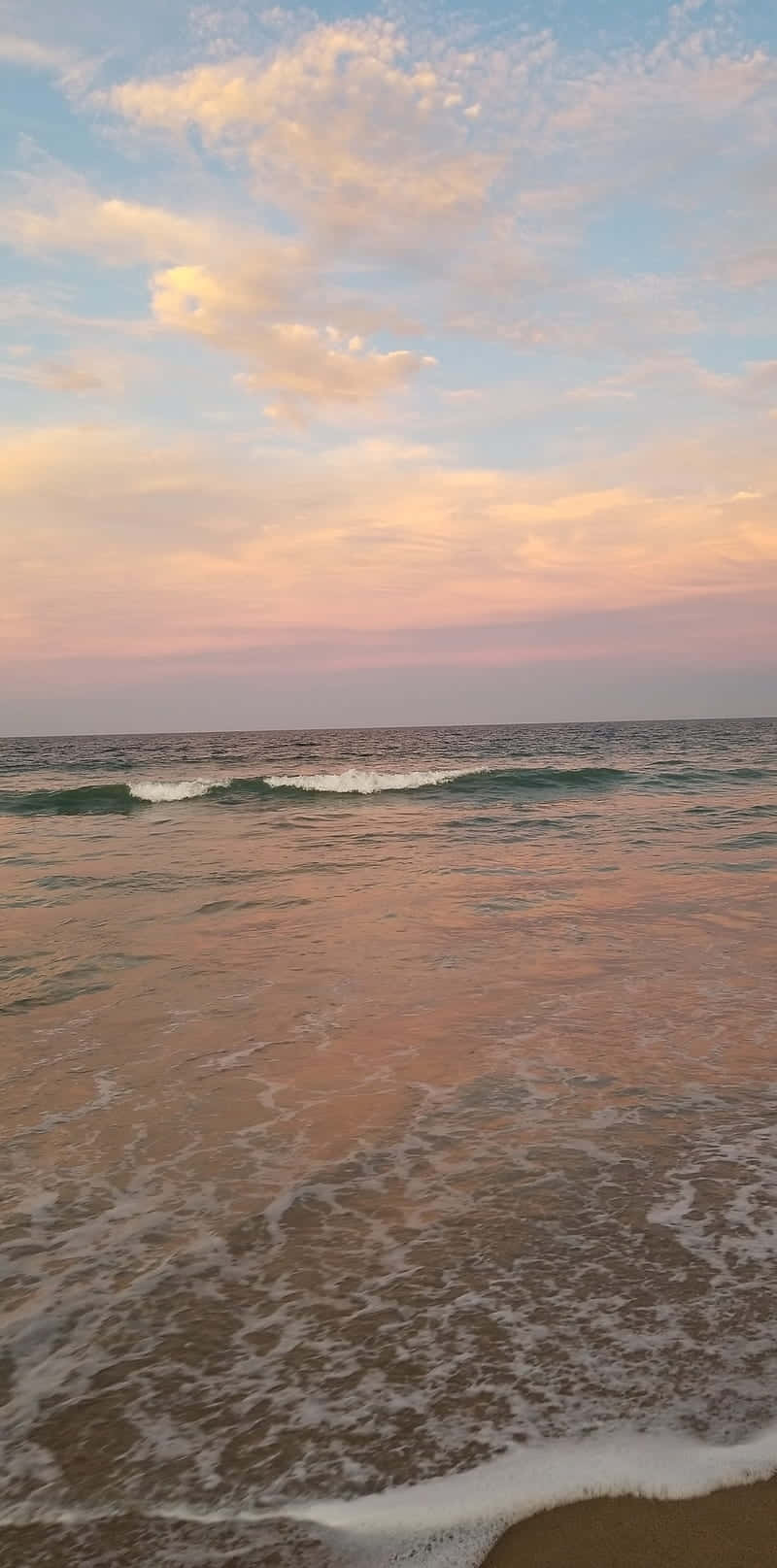 Ocean Aesthetic Phone 桌布 壁紙 — 夕陽將海洋天空染成柔和的粉紅色和金色，溫柔的海浪拍打著沙灘。