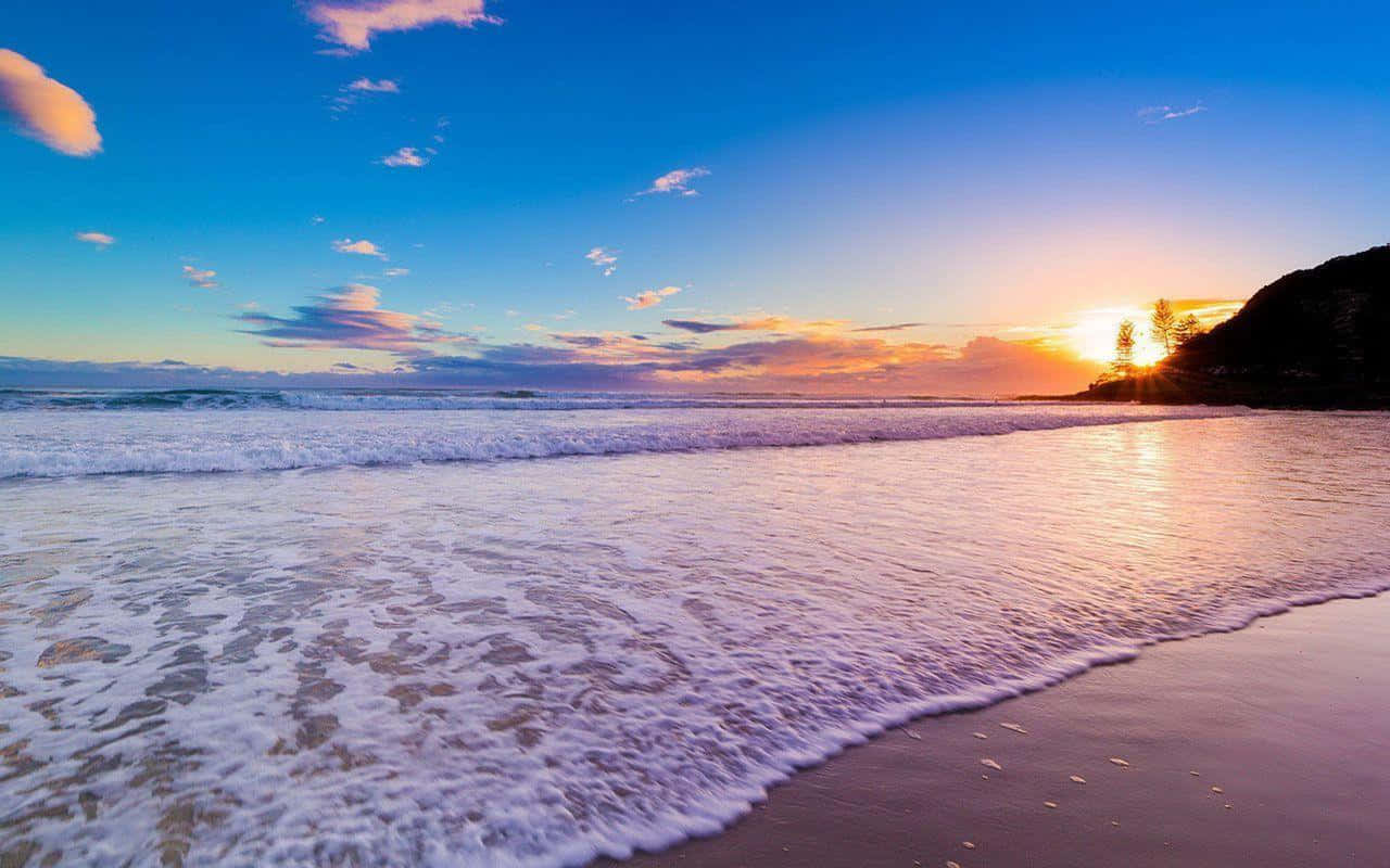 Best Summer 桌布 壁紙 — 夕陽將海洋染成金色，海浪在充滿活力的天空下拍打沙灘。
