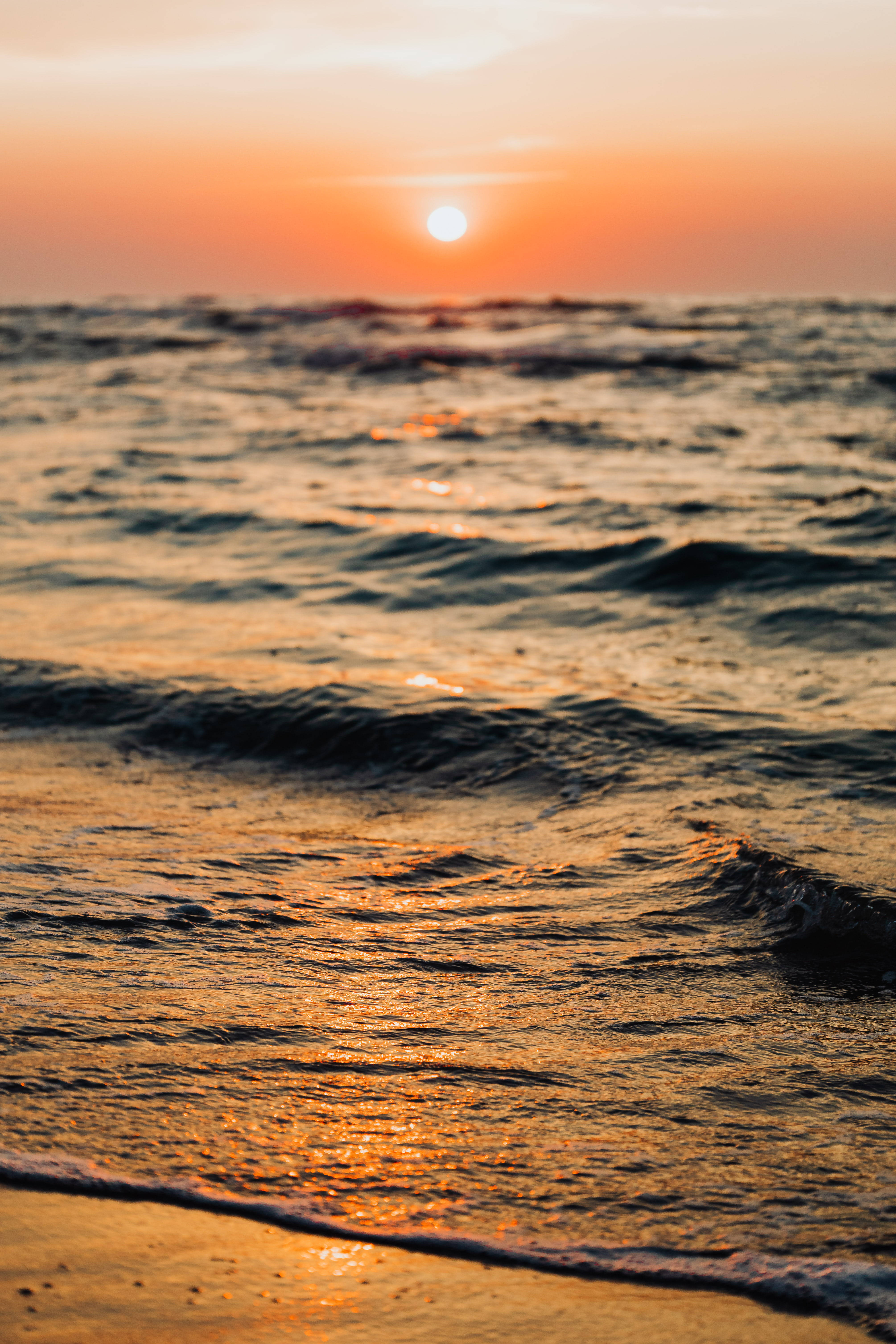 Wave 桌布 壁紙 — 夕陽將海浪染成溫暖的橙色和金色，輕輕拍打著海岸。