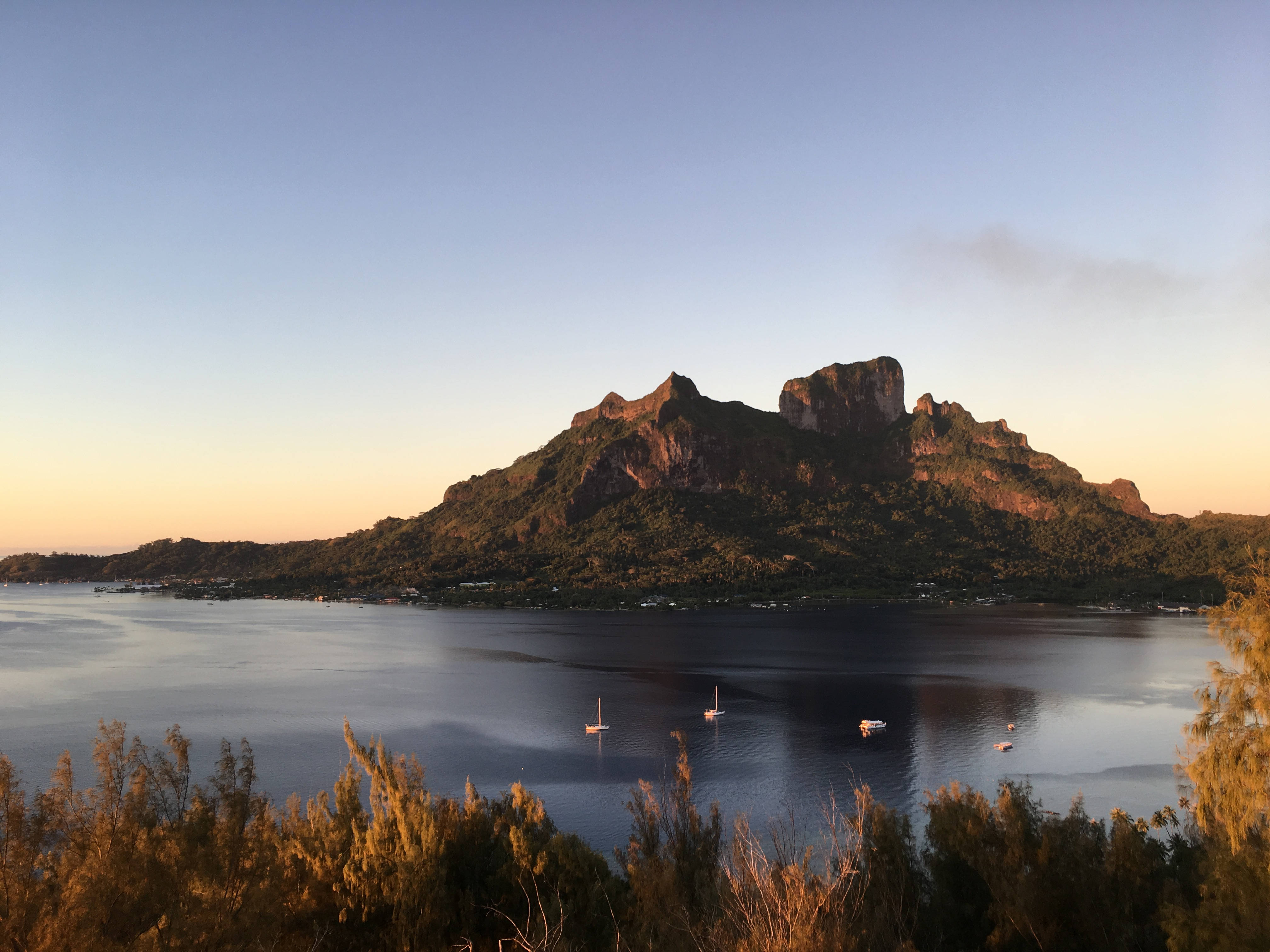 french 桌布 壁紙 — 夕陽將熱帶海灣沐浴在溫暖的金色中，帆船在崎嶇的山島附近漂流。