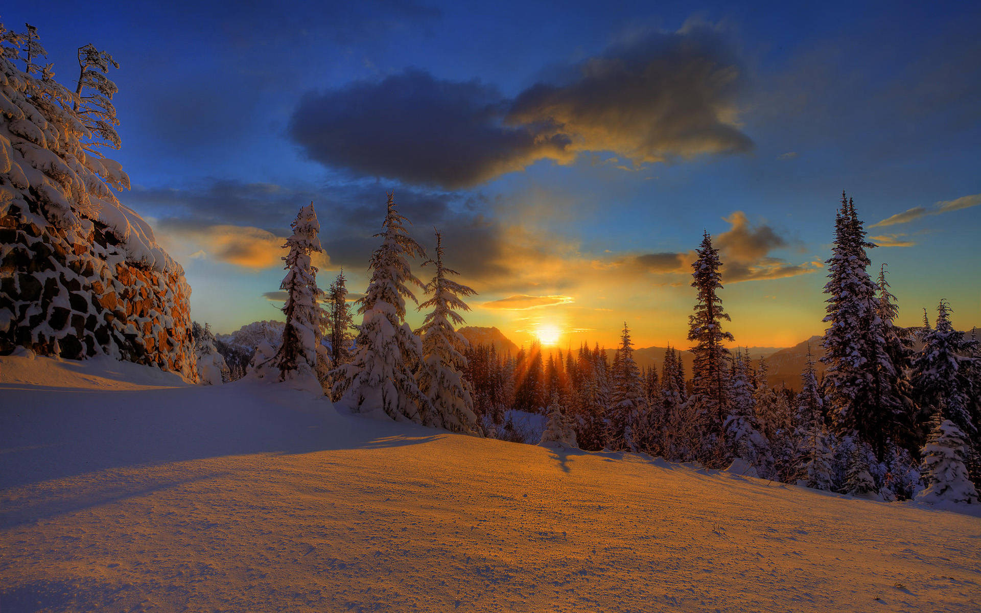 高清 桌布 壁紙 — 夕陽將白雪覆蓋的松樹和山脈染成溫暖的金色，襯托著深藍色的天空和戲劇性的雲彩。