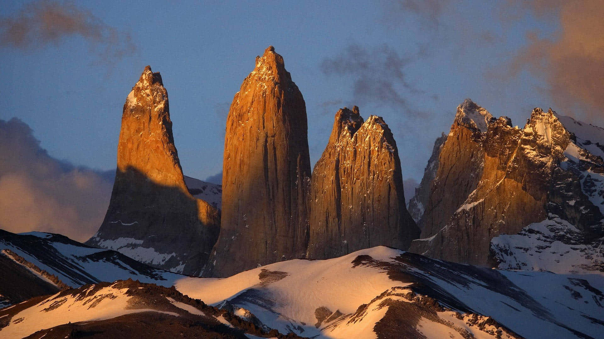 Patagonia 桌布 壁紙 — 夕陽將百內國家公園標誌性的花崗岩山峰沐浴在金色光芒中，映襯著暮色天空。