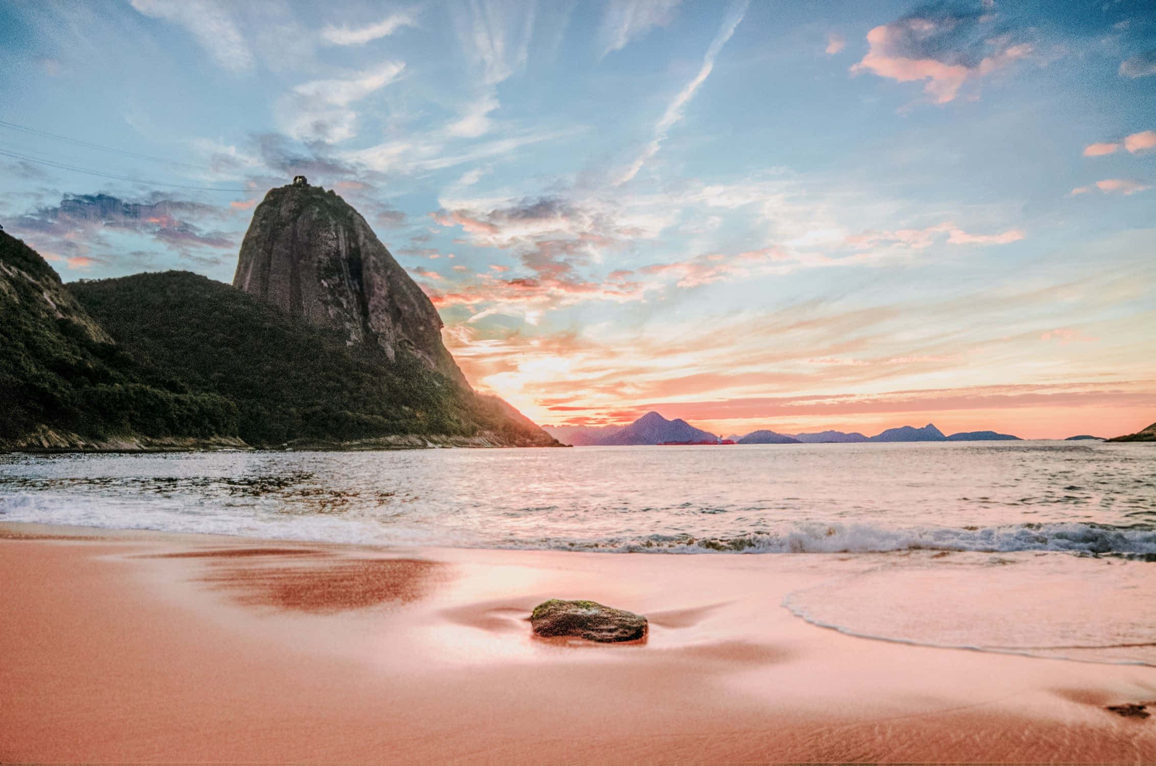 Tumblr Photography 桌布 壁紙 — 夕陽將糖粉色的沙灘和天空染上色彩，海浪拍打著標誌性的糖麵包山山腳。