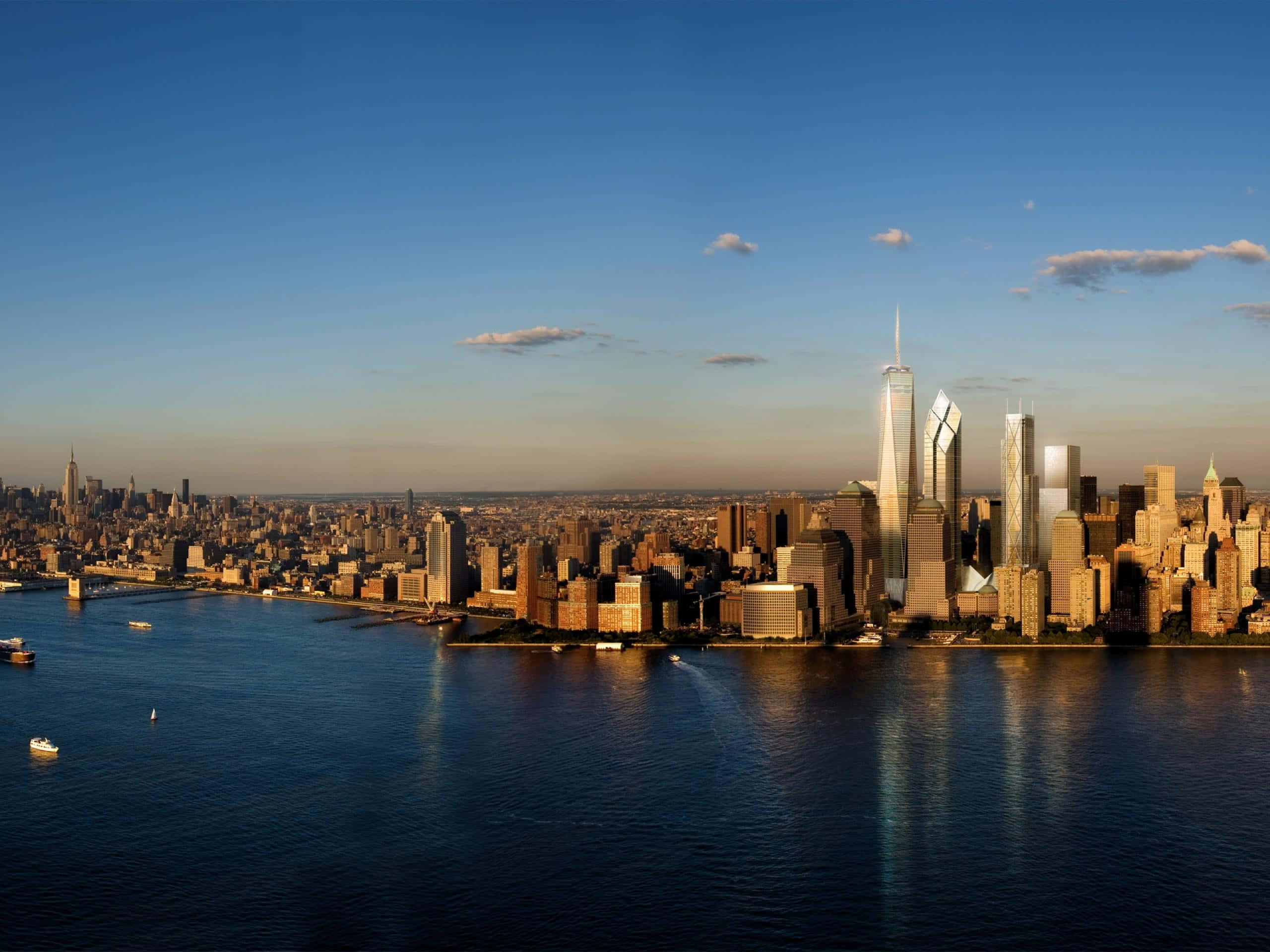 New York 桌布 壁紙 — 夕陽將紐約天際線沐浴在金色光芒中，光線在哈德遜河上反射，船隻在高聳的摩天大樓下滑行。