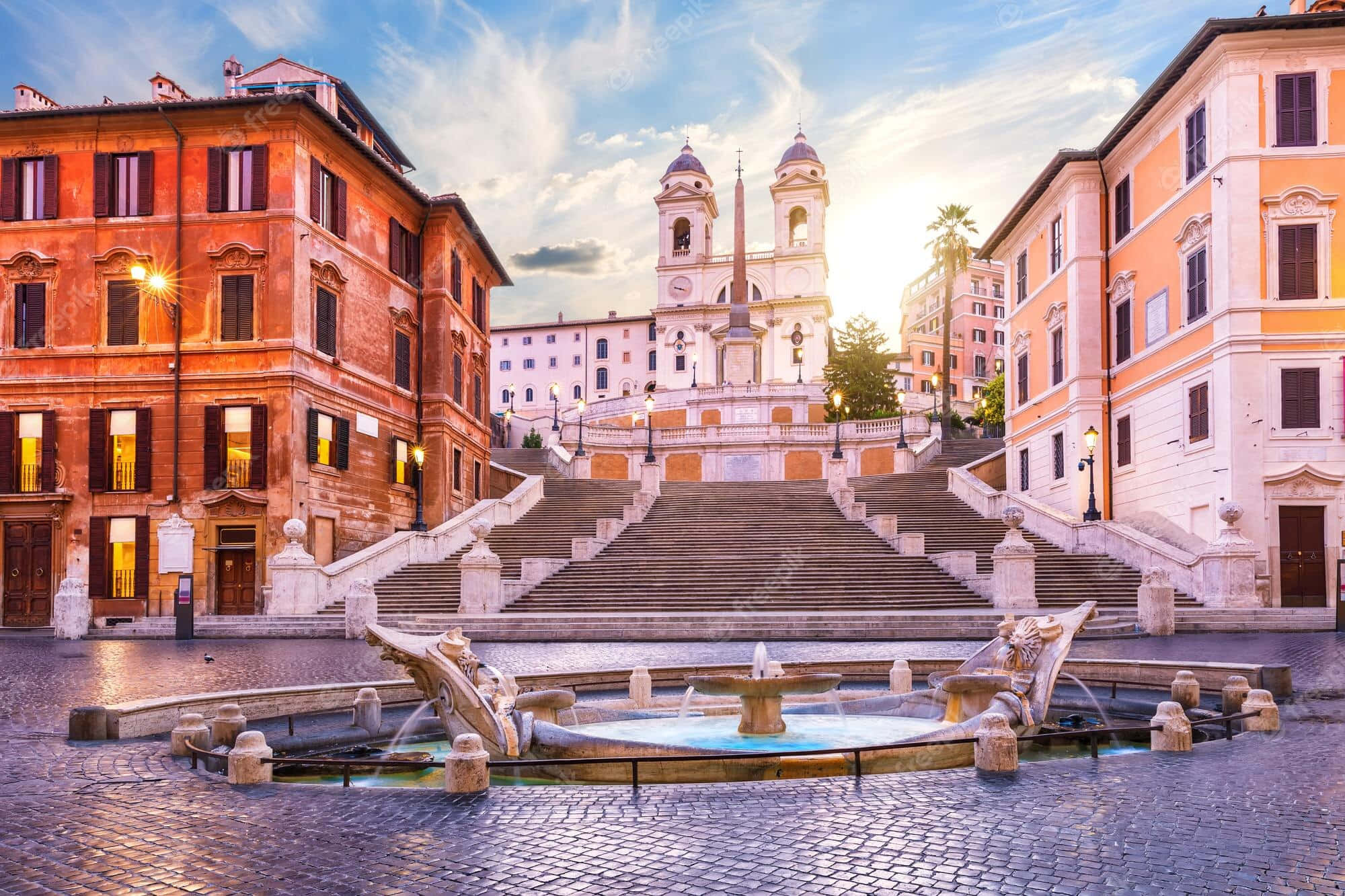 stairs 桌布 壁紙 — 夕陽將西班牙階梯和聖三一教堂沐浴在金色光芒中，前景是鵝卵石噴泉。