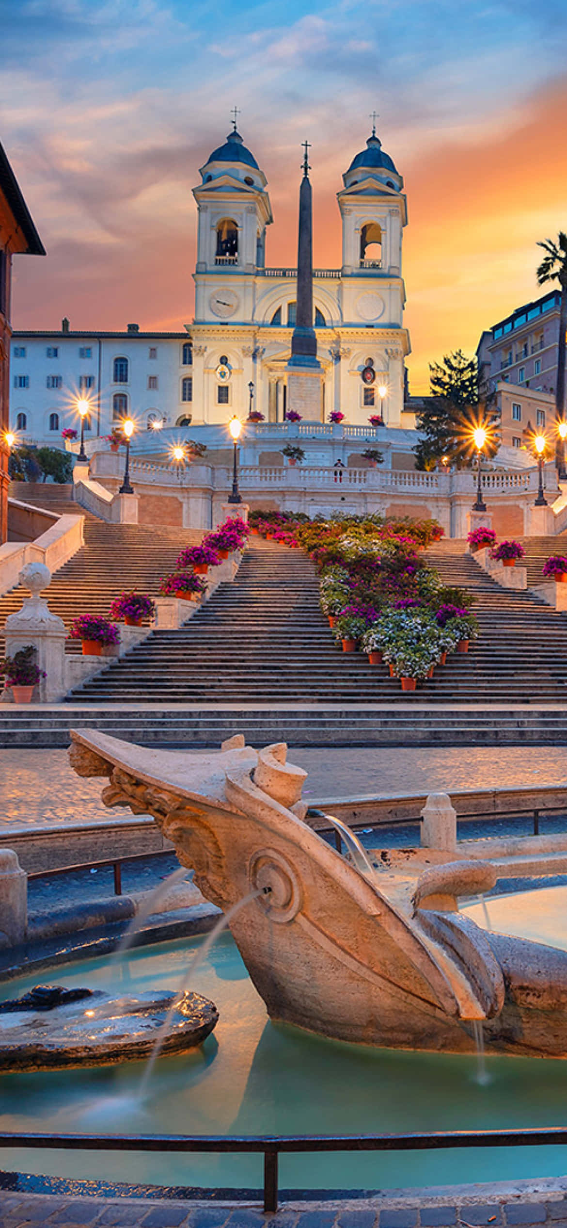 stairs 桌布 壁紙 — 夕陽將西班牙階梯和聖三一教堂沐浴在溫暖的光線中，噴泉和花盆點綴著宏偉的階梯。