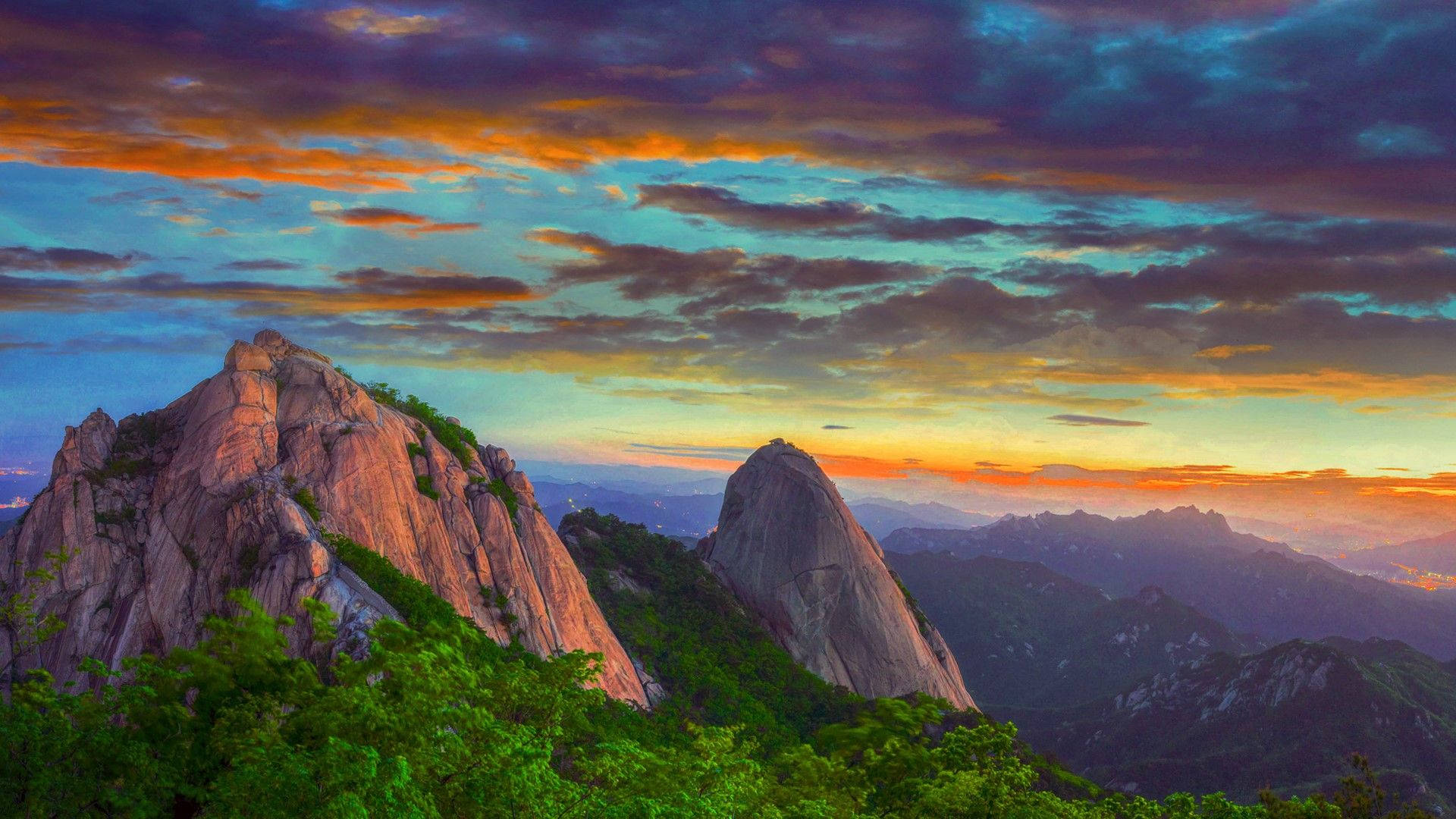 山脈 桌布 壁紙 — 夕陽將鋸齒狀的山峰染成火熱的橙色和紫色，雲彩劃過暮色天空。