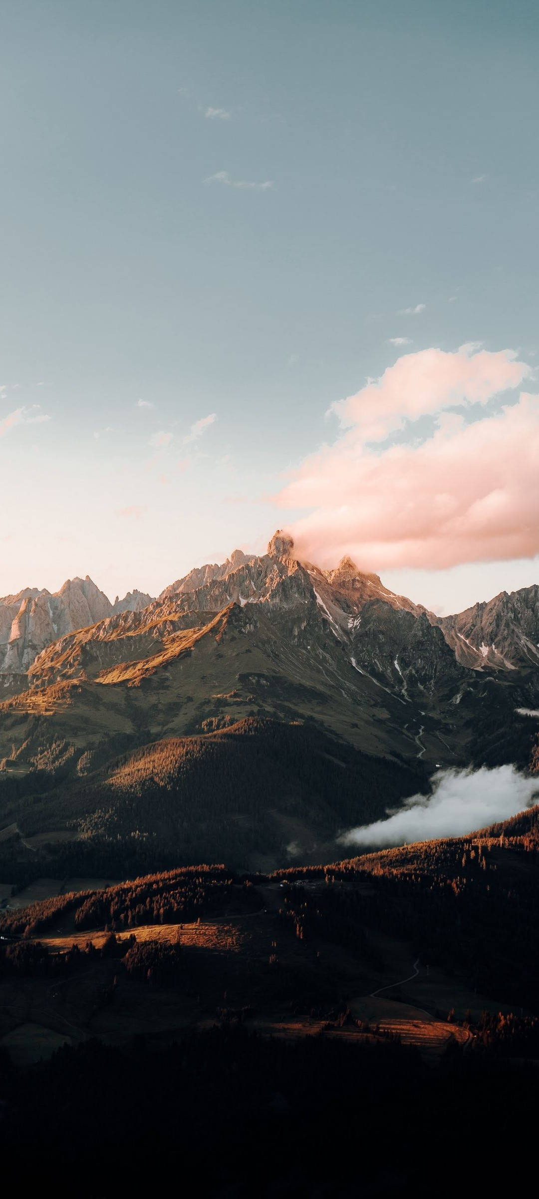 Mountain Landscape 桌布 壁紙 — 夕陽將鋸齒狀的山峰沐浴在溫暖的金色中，柔和的粉紅色雲朵飄過被陰影籠罩的山谷。