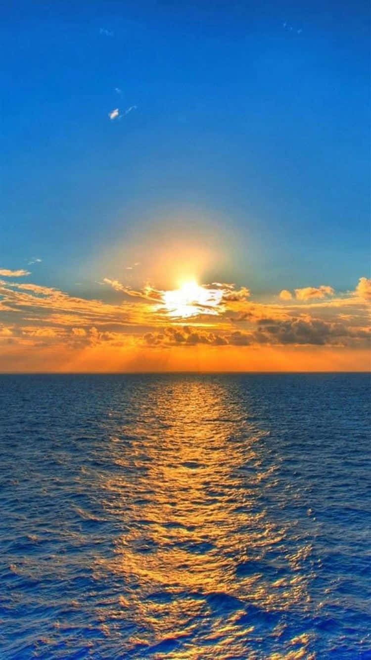 Sunrise iPhone 桌布 壁紙 — 夕陽映照海洋，金色光線穿過雲層，反射在漣漪的藍色水面上。