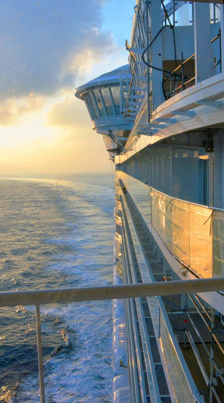Cruise 桌布 壁紙 — 夕陽溫暖地照耀著海洋，一艘郵輪的玻璃甲板和欄杆劃破地平線。