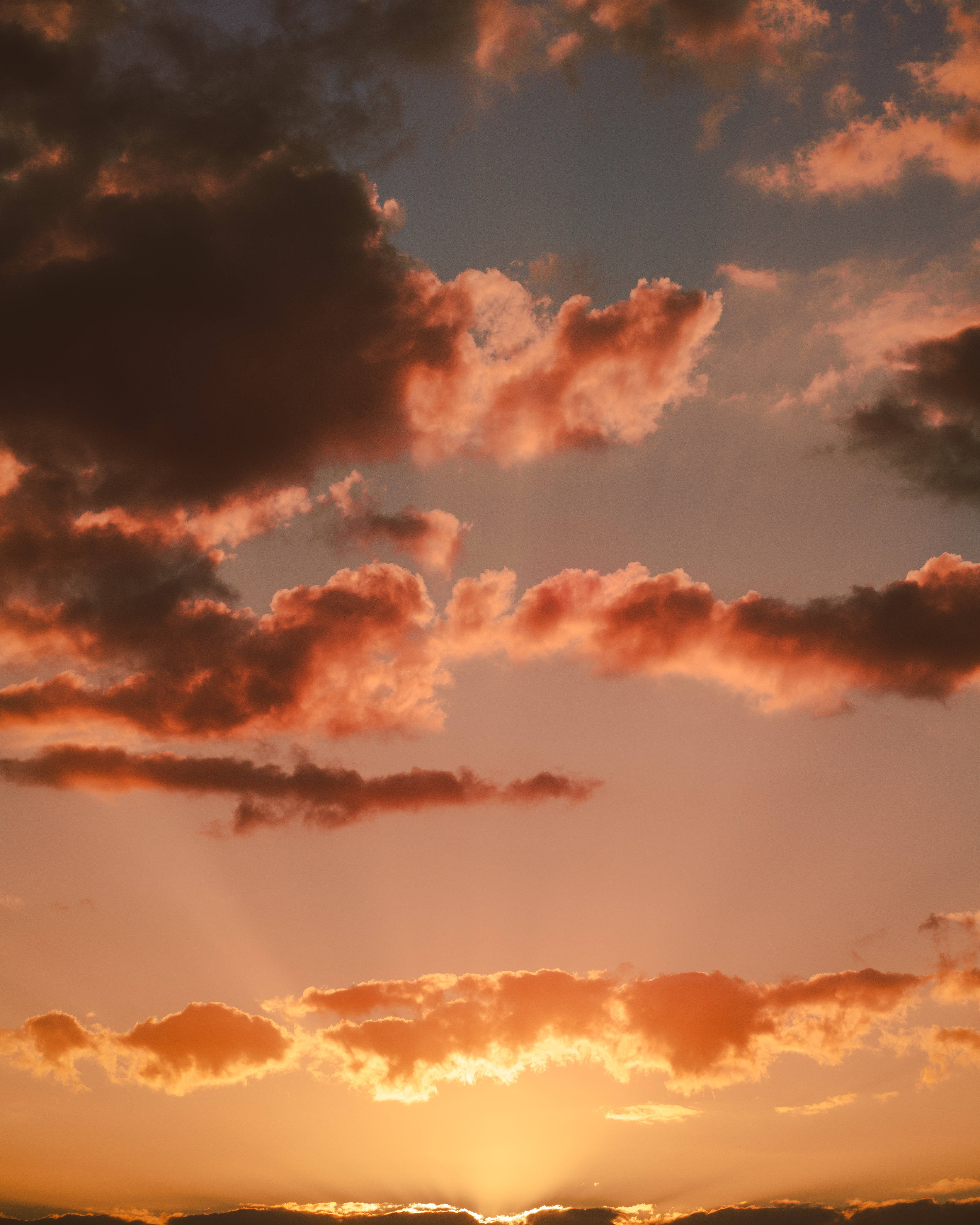 Beautiful Sky 桌布 壁紙 — 夕陽穿透戲劇性的橙色和深色雲層，映照在溫暖的漸變天空上。